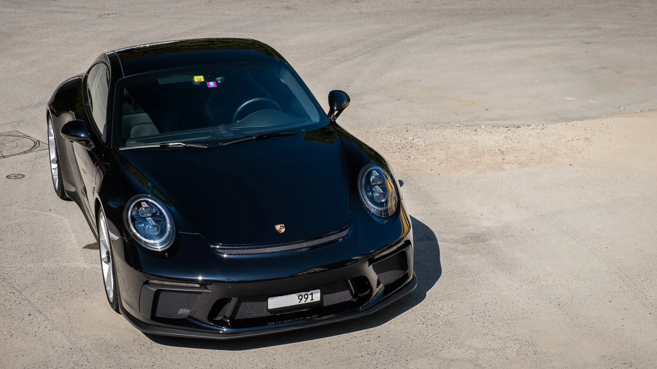 Schwarzer Porsche 911 auf einer unbefestigten Straße, Blick von oben.