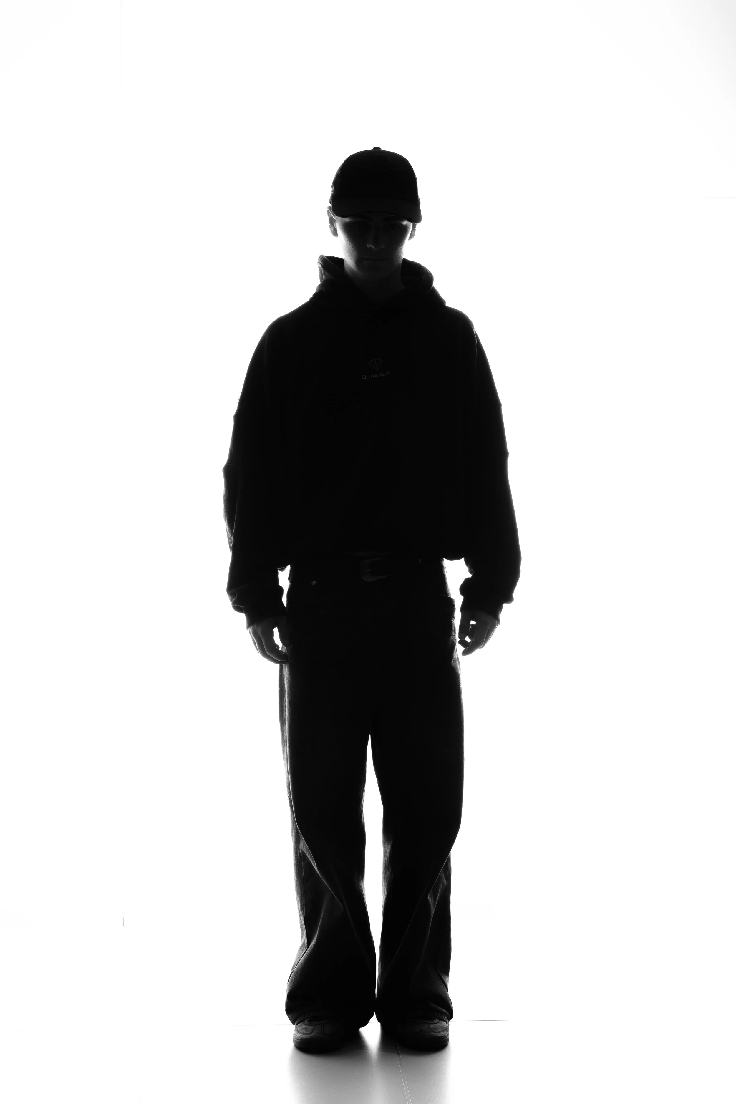 Silhouette einer Person mit Baseballkappe, die vor einem hellen Hintergrund steht.