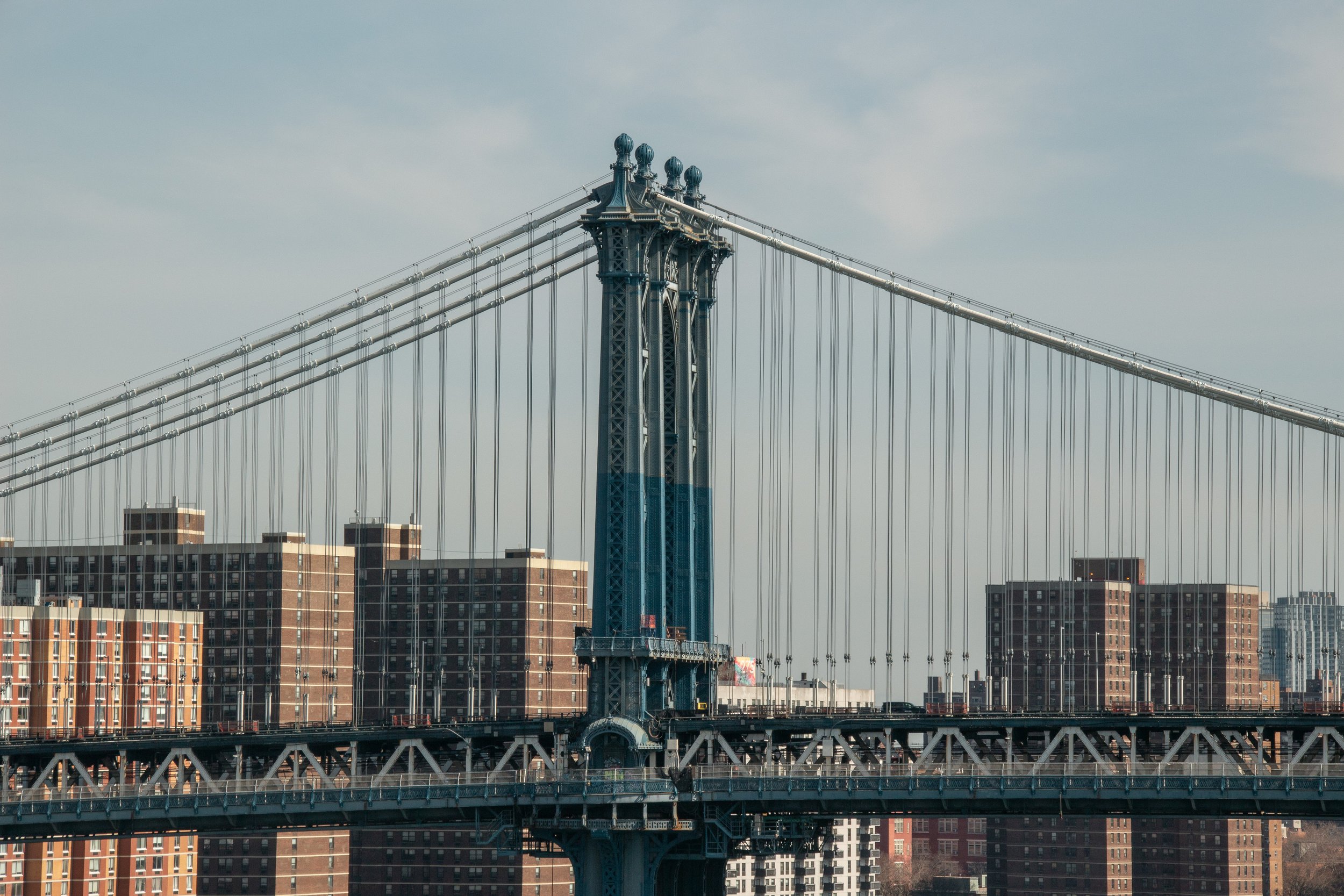Blick auf die Brooklyn Bridge in New York mit Gebäuden im Hintergrund an einem Tag mit bewölktem Himmel.
