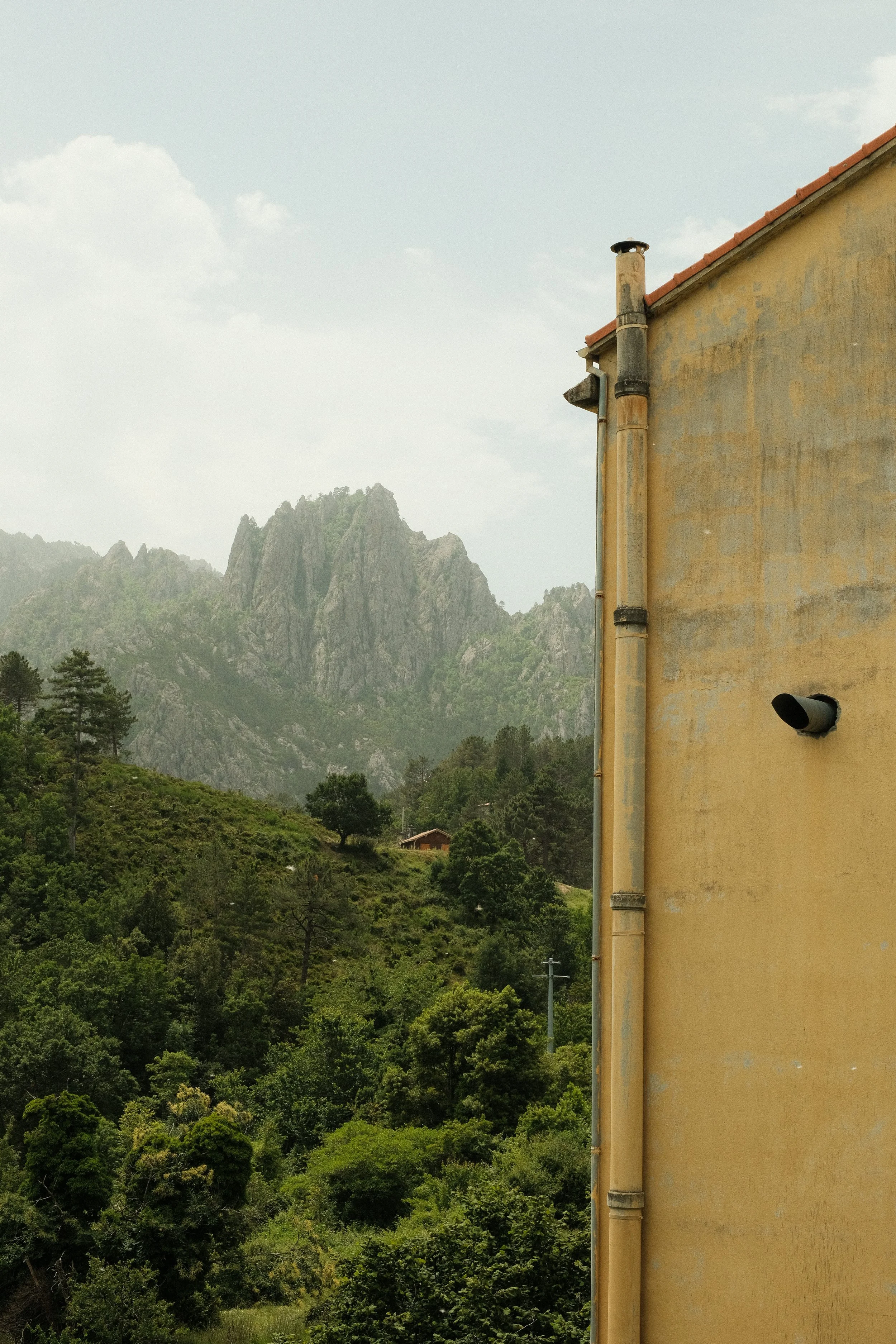 Ansicht eines Hauses mit Sicht auf grüne Hügel und Berggipfel im Hintergrund