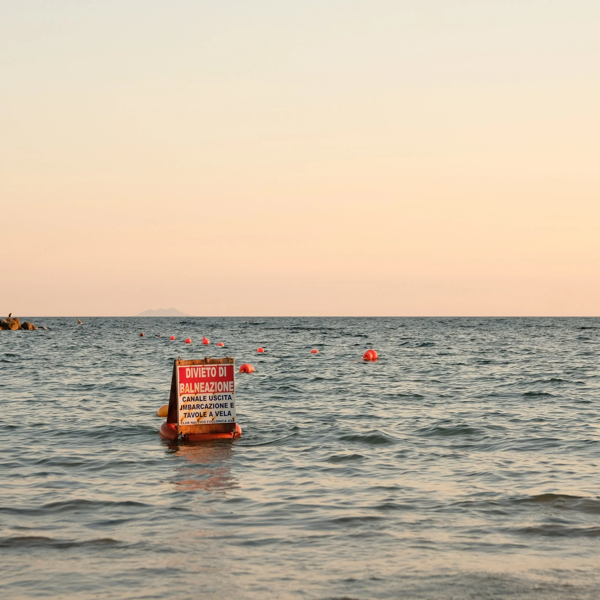 Das Meer mit einem roten Verbotsschild auf Wasserbojen, das das Baden verbietet.