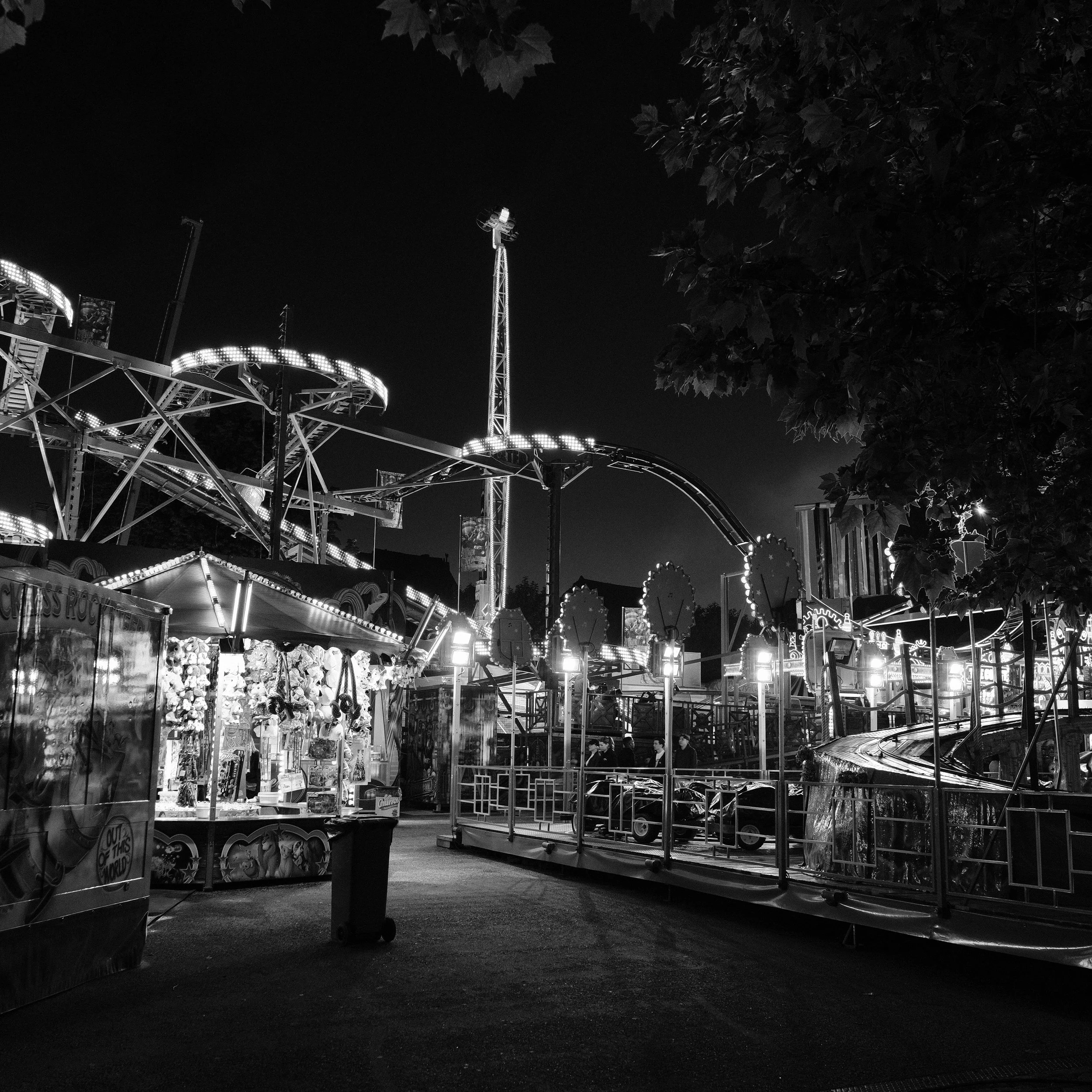 Lichter auf einem nächtlichen Jahrmarkt, Karussell und Fahrgeschäfte, keine Menschen sichtbar.