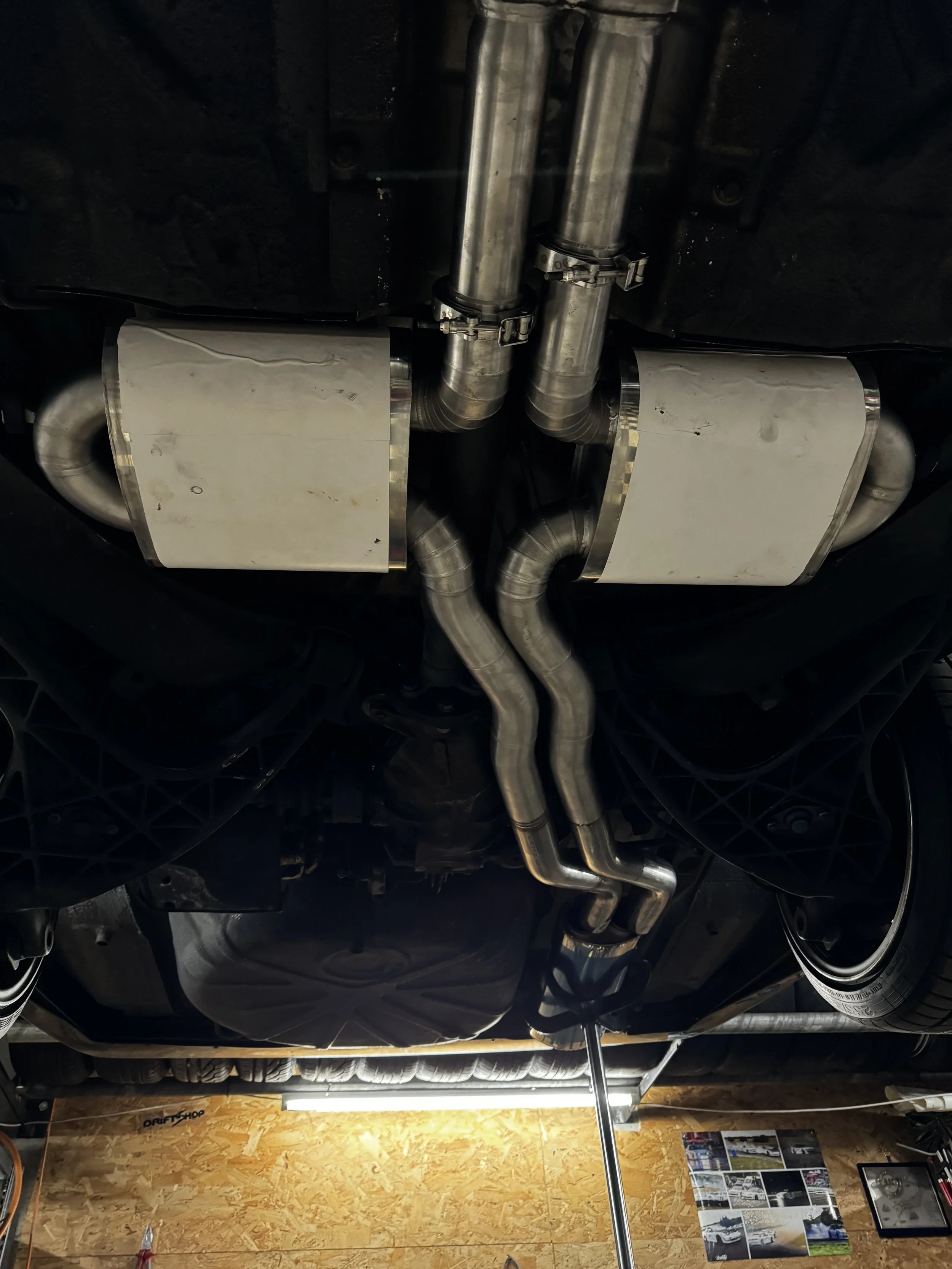 Unterseite eines Autos mit Auspuffanlage und Rohren.