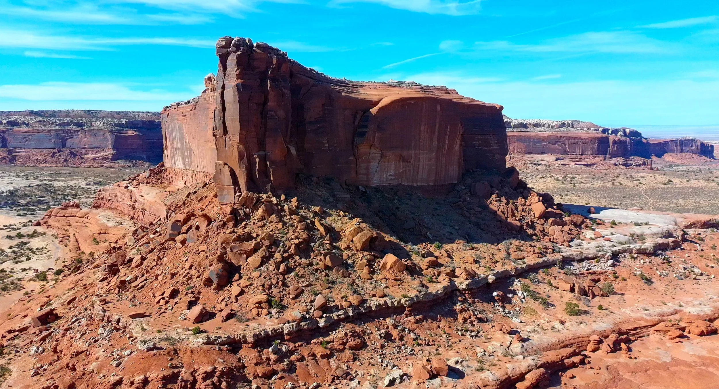 Red rock formation in a desert landscape under a blue sky.