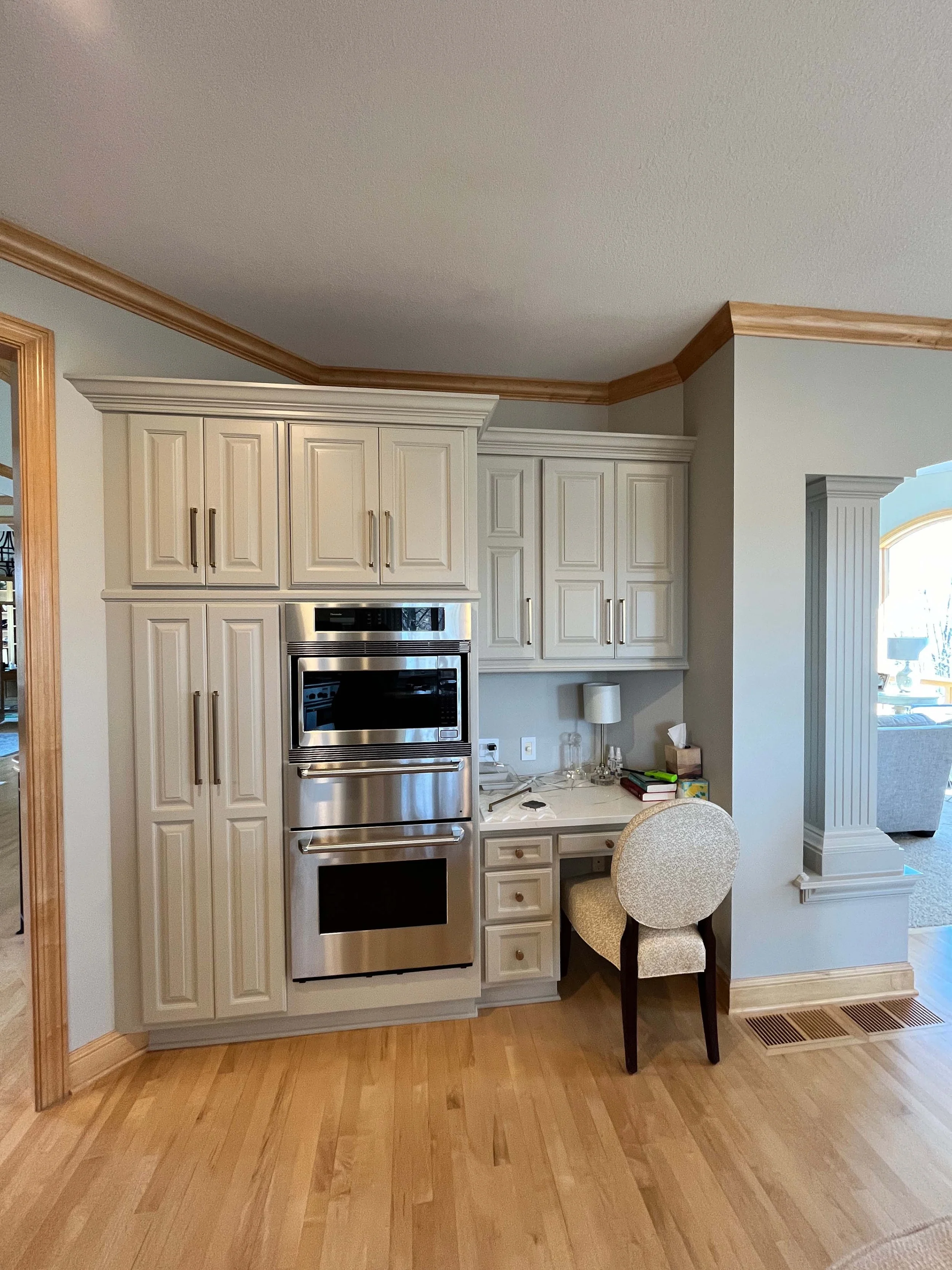 Bright residential kitchen featuring custom-painted white cabinetry and a built-in workspace.