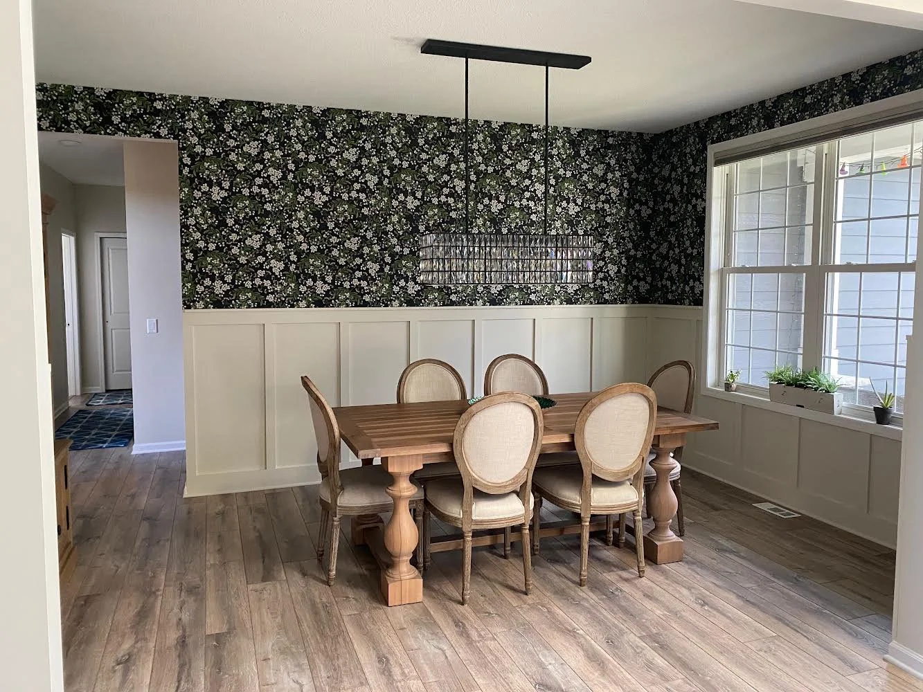 A formal dining room featuring white wainscoting and black and white floral wallpaper installed by professional interior painters in MN.