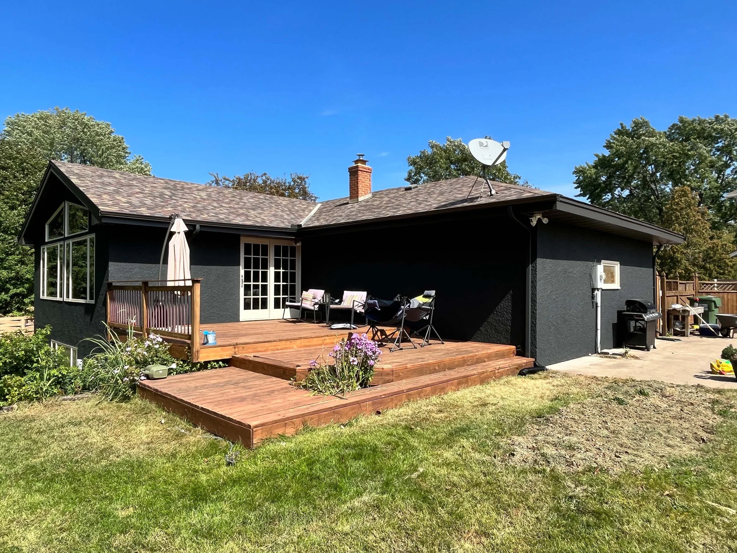 Rear view of a residential home with a professional dark gray exterior paint finish and wooden deck, completed by painting contractors in Minneapolis.
