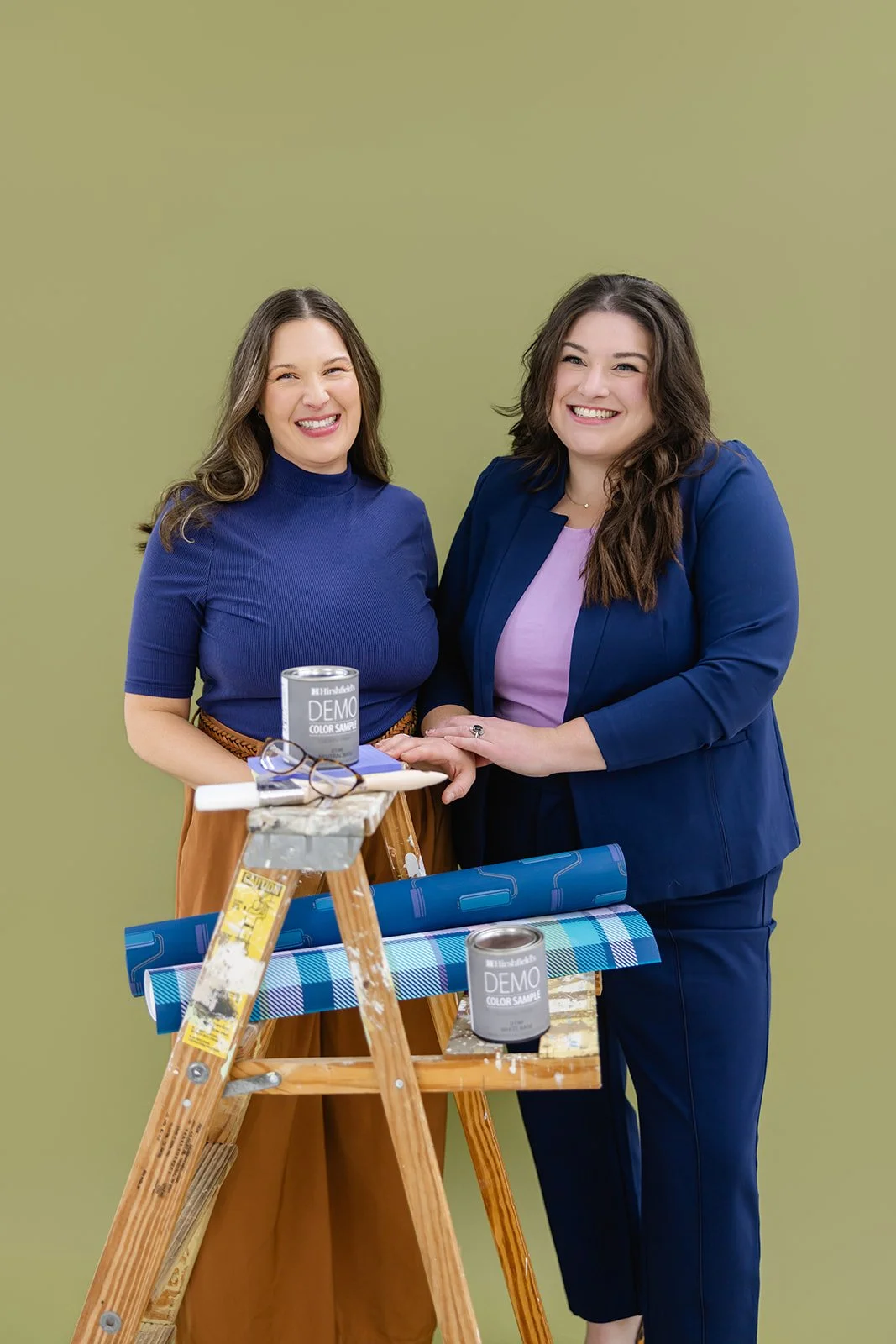 Founders of The List, a women-owned painting company in Minneapolis, MN, posing with paint cans and wallpaper rolls.