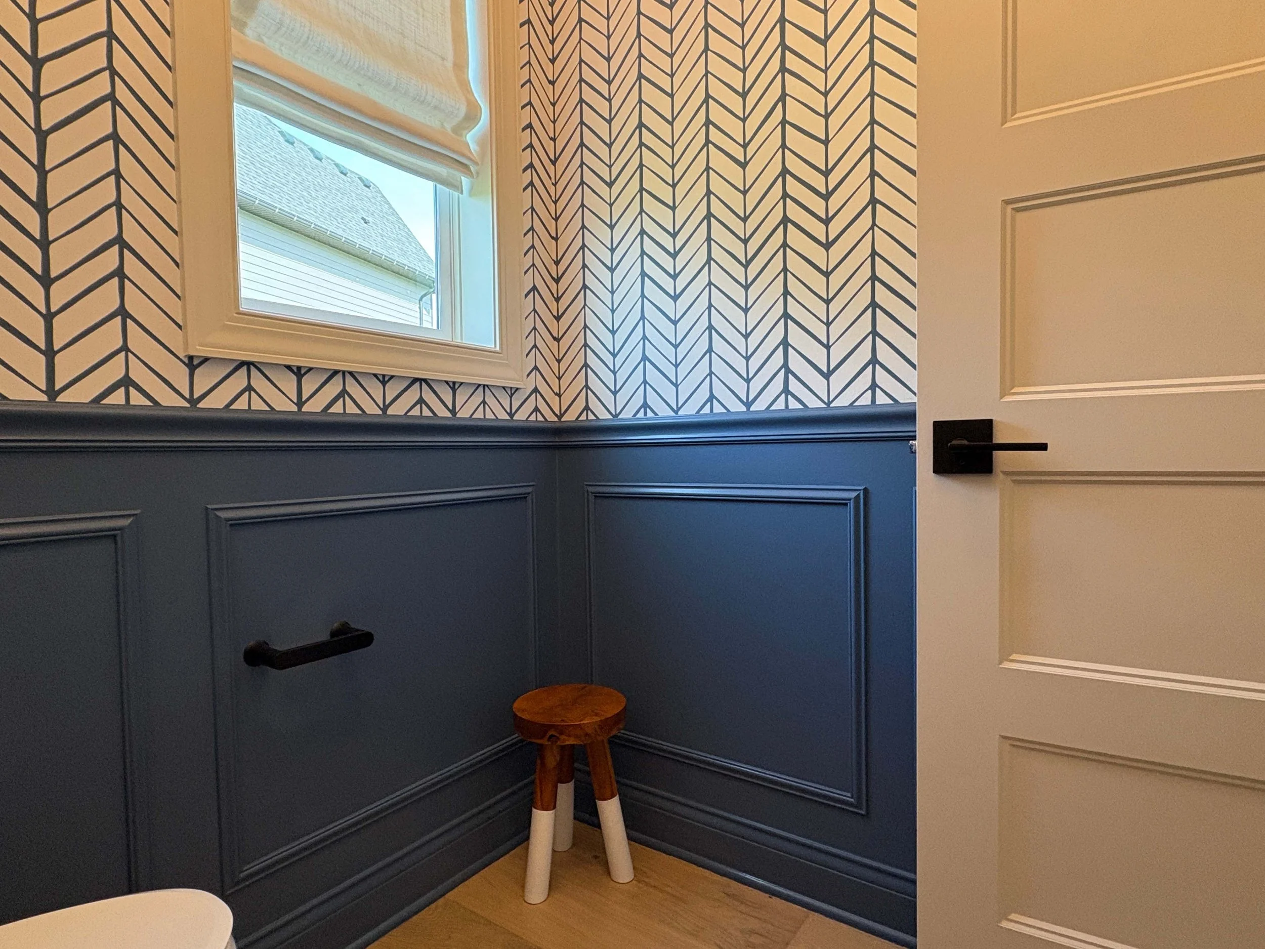 A bathroom featuring blue wainscoting and custom herringbone wallpaper, highlighting professional interior painting and specialty finishes in MN.