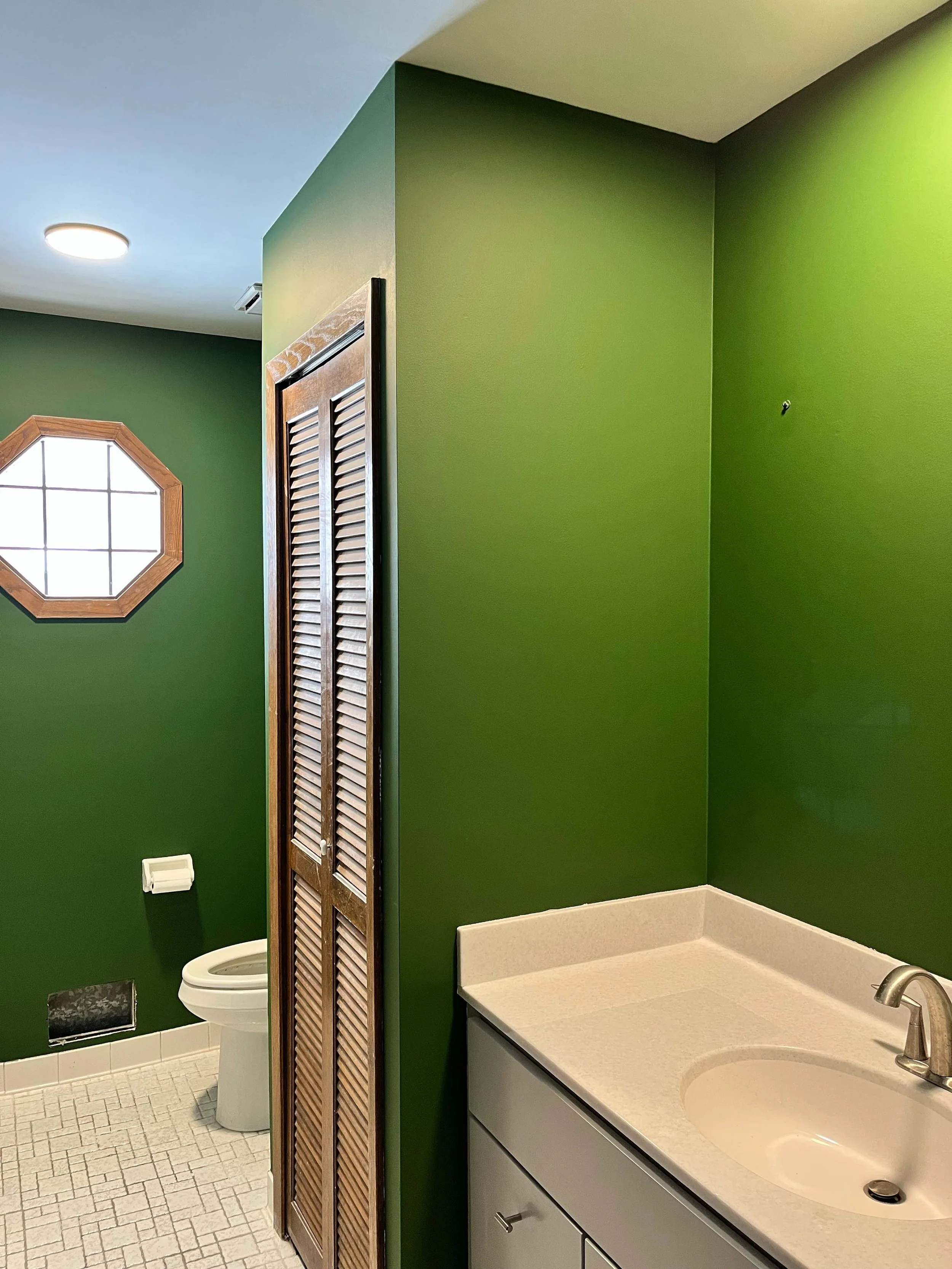 A professionally painted bathroom featuring vibrant deep green walls and crisp white trim, showcasing market-ready results from painting services for realtors in Minneapolis.