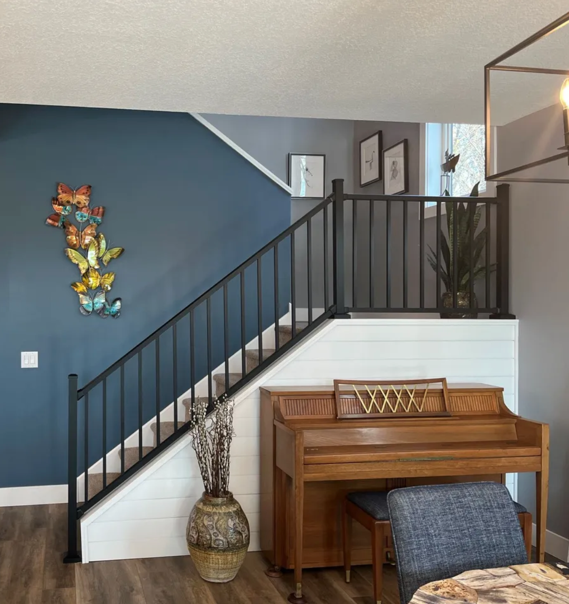 A modern interior featuring a dark blue accent wall and black staircase railing professionally painted by painting contractors in Minneapolis.
