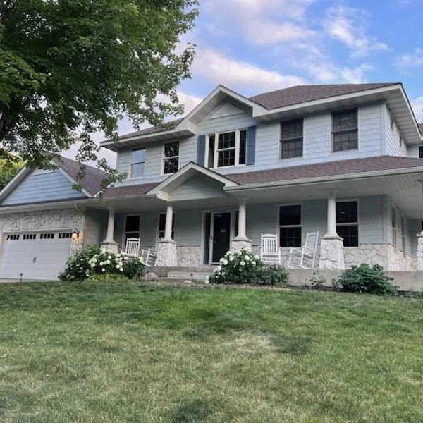 Professional exterior painting of a blue residential home with a white front porch and trim by The List in Minneapolis, MN.