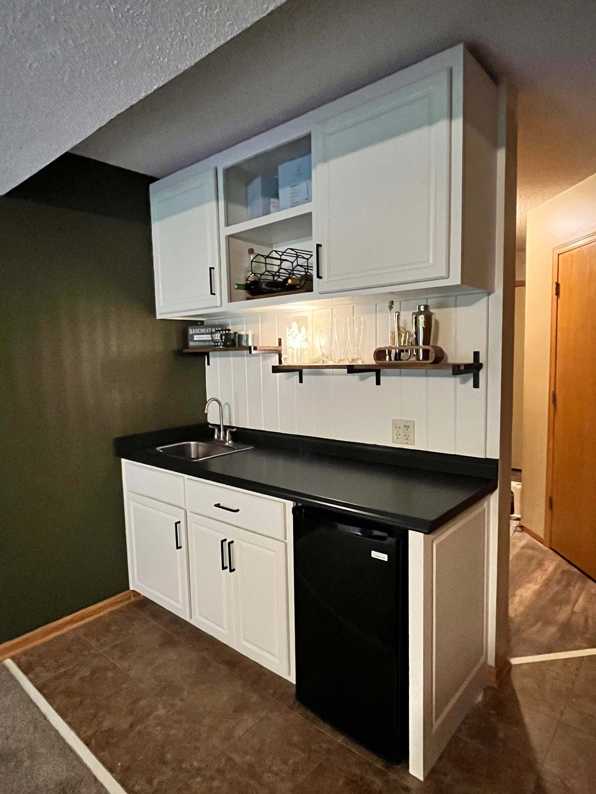 Custom basement renovation featuring a contrast-painted bar area and expert custom wall finishes.