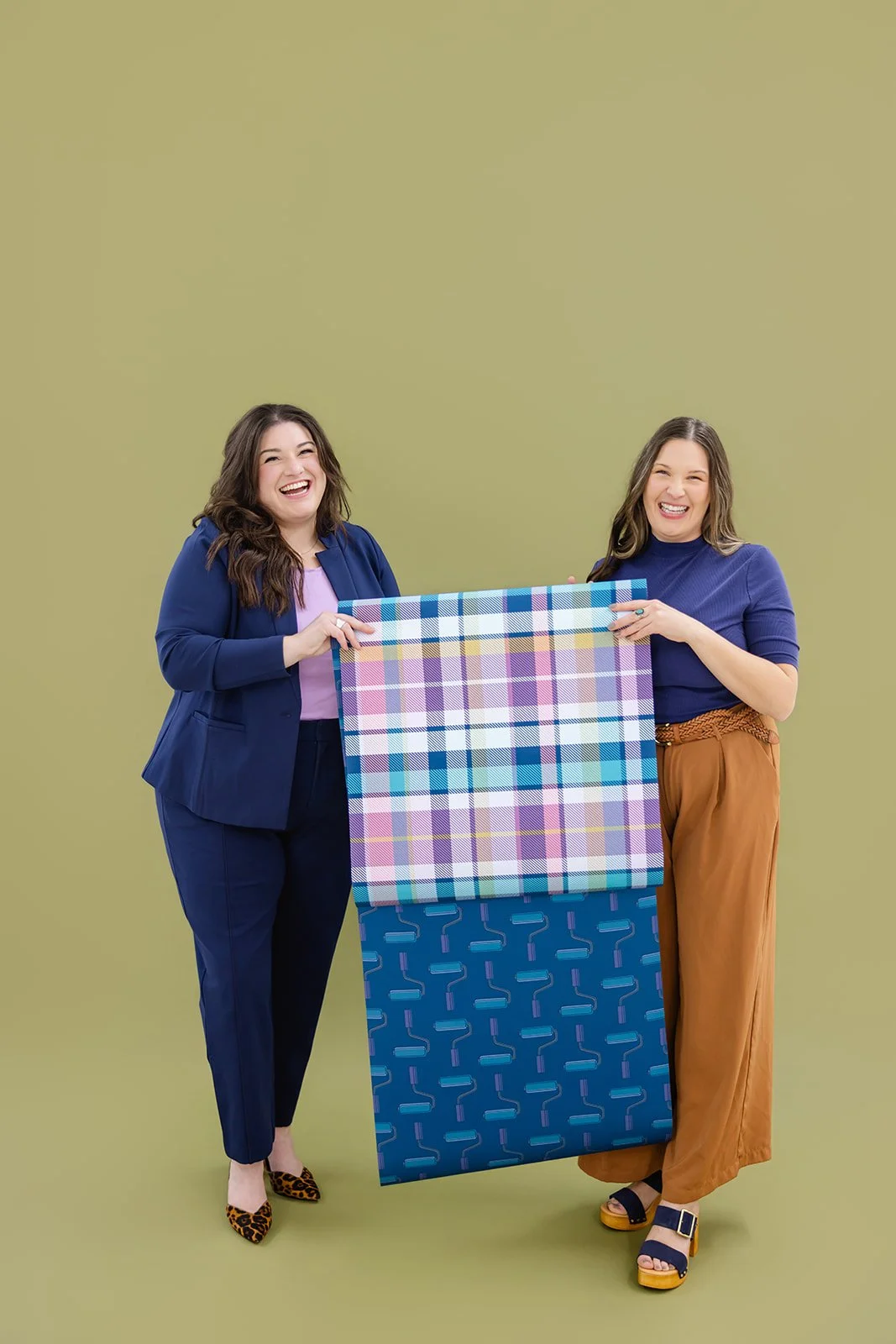 The professional founders of The List holding a colorful plaid wallpaper sample, representing expert interior painting and wallpaper services in Minneapolis.