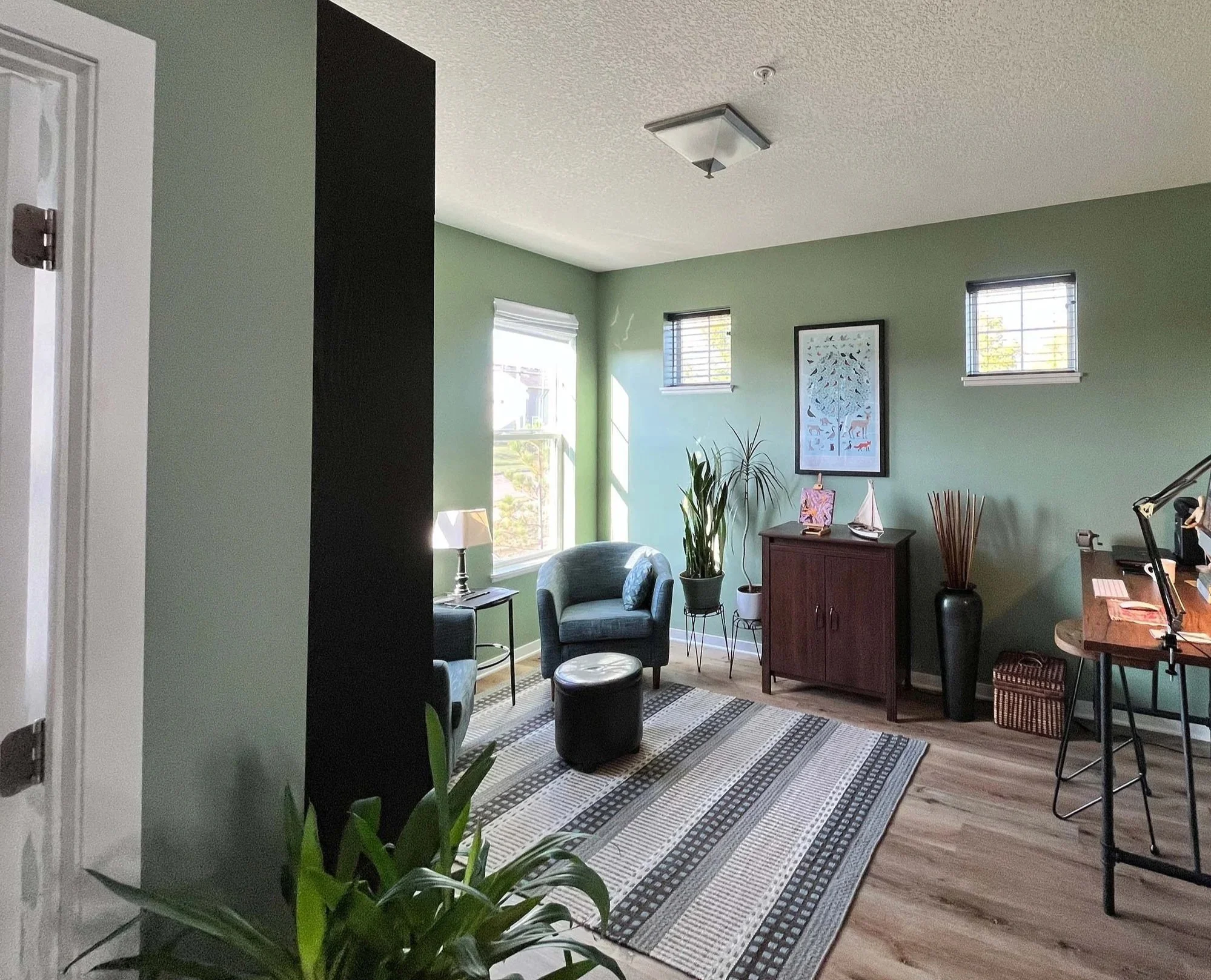 A modern home office with sage green walls and a black accent pillar, professionally finished by painting contractors in Minneapolis.