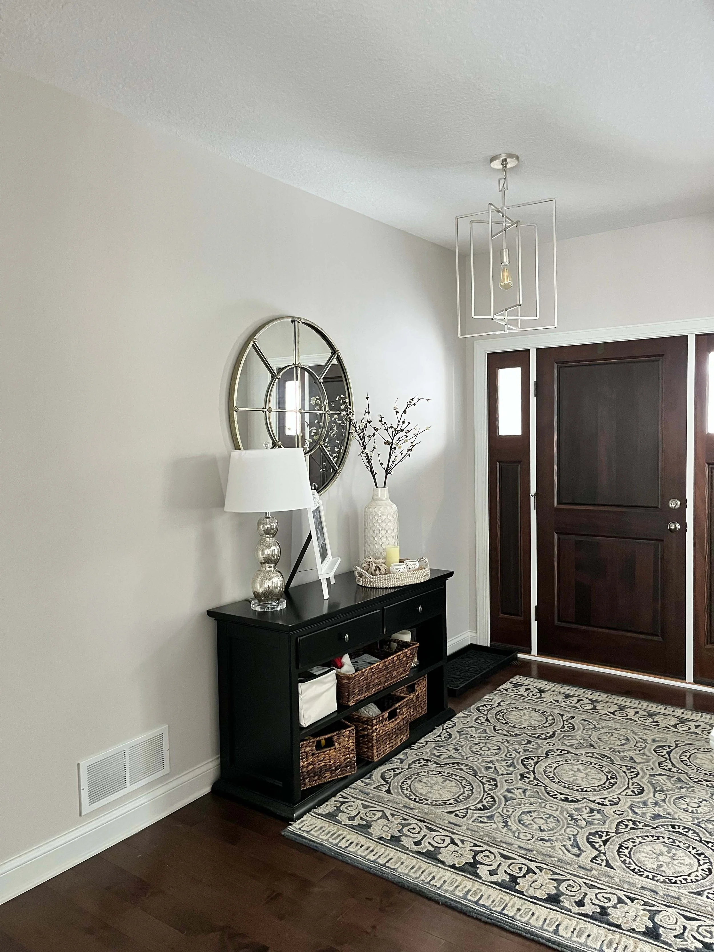 Neutral toned entryway professionally painted by house painters in Minneapolis, featuring a dark wood door and console table.