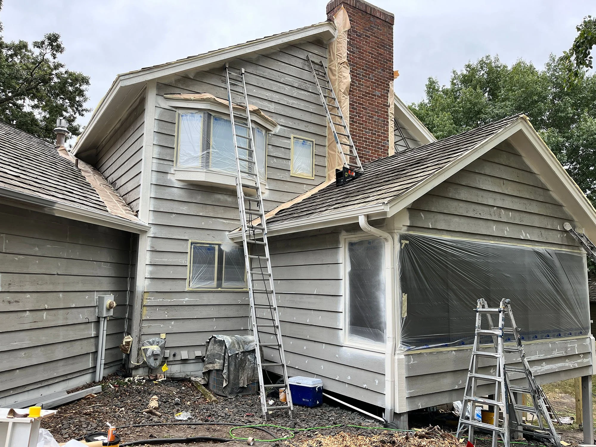 Gray house in the process of exterior painting done by The List painting contractors