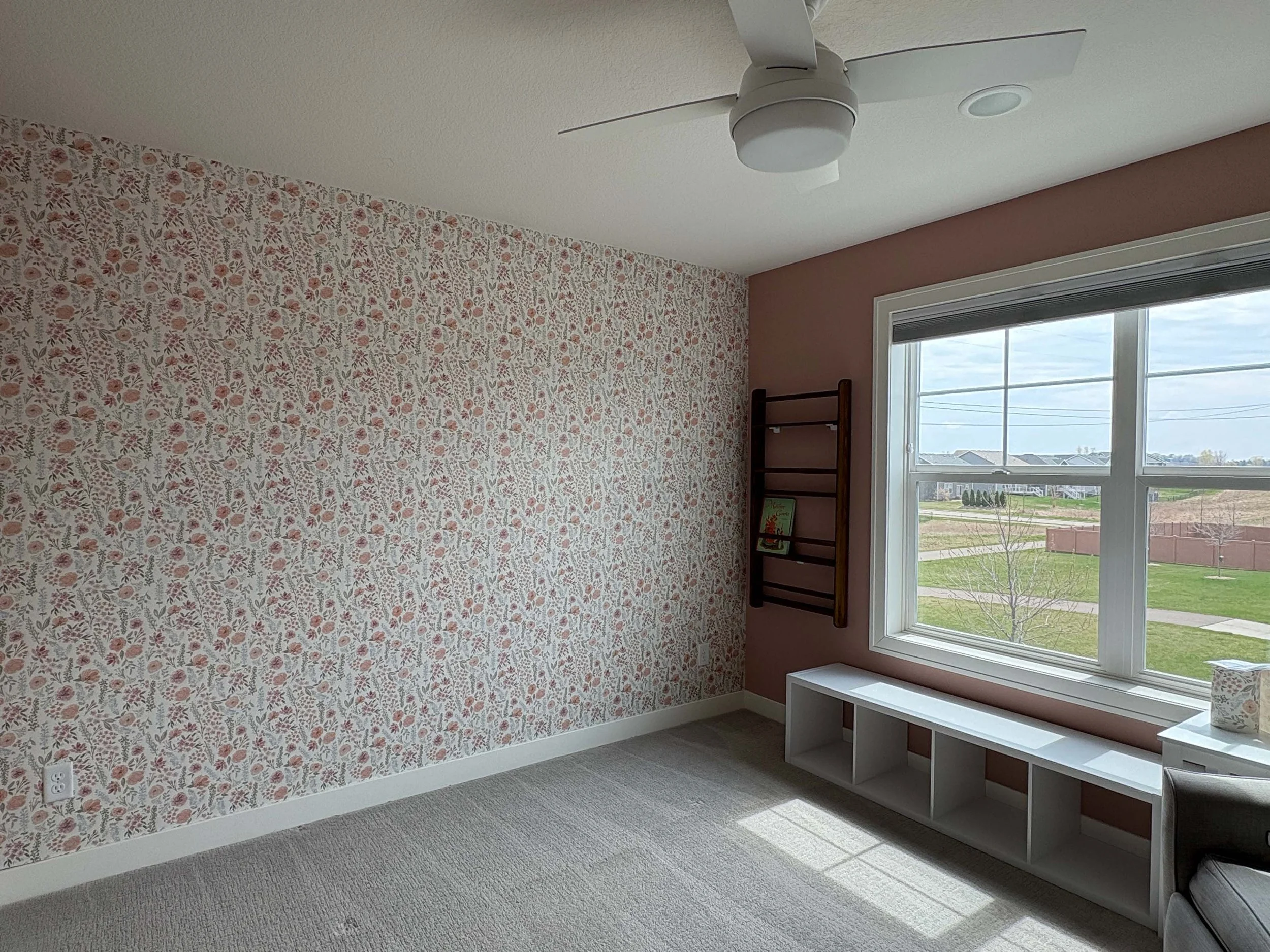 A serene residential bedroom featuring a delicate floral accent wall applied by an expert wallpaper installer.