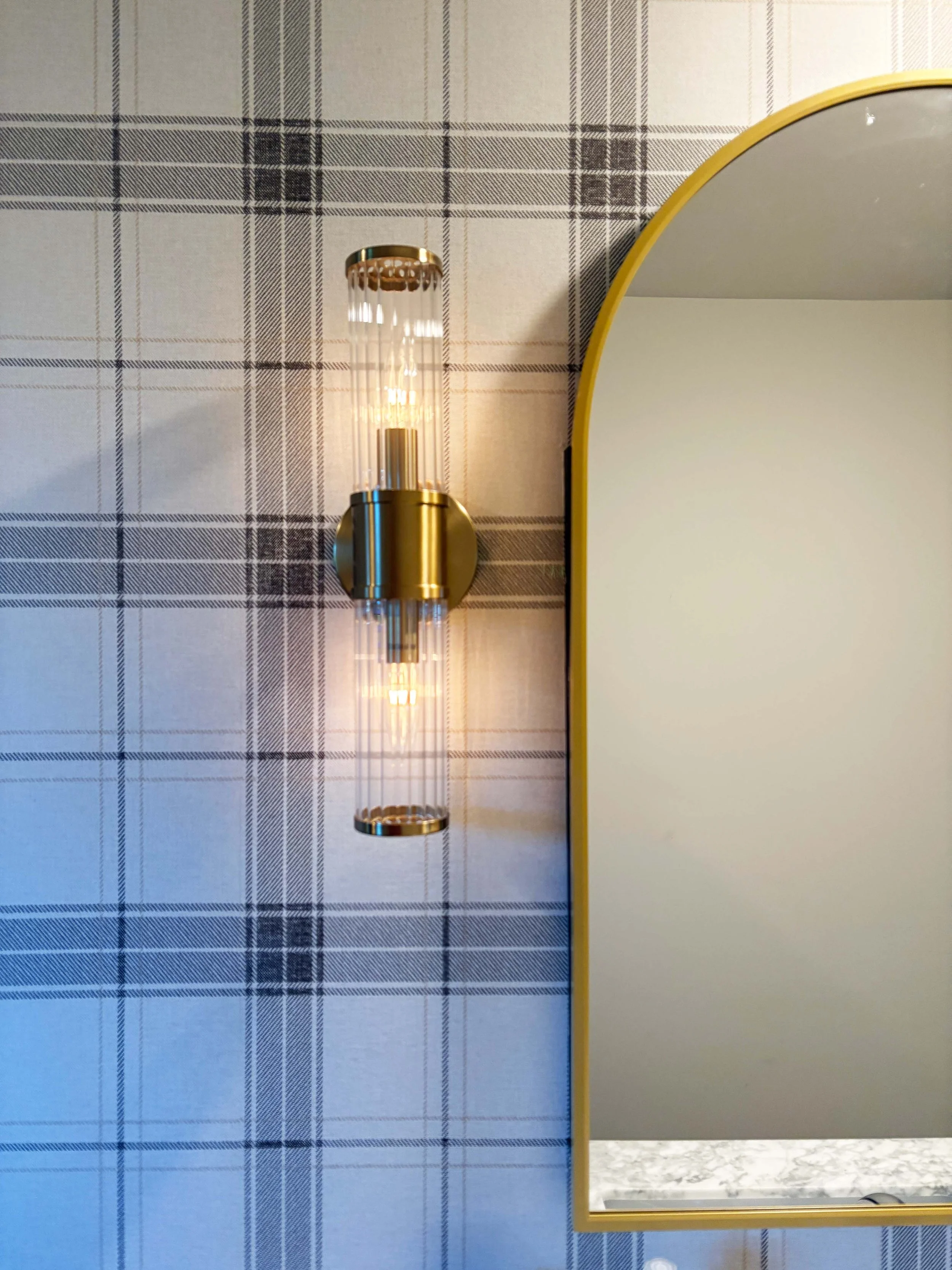 Close-up of a bathroom featuring custom plaid wallpaper and a gold arched mirror, showcasing professional specialty finishes and interior painting in MN.