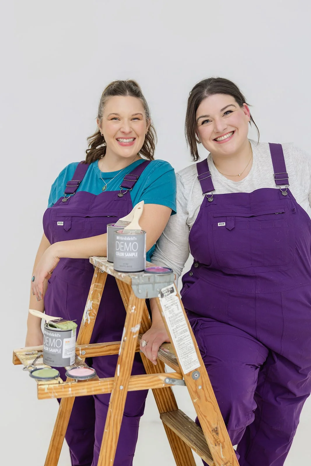 The founders of The List, professional house painters in Minneapolis, posing with painting supplies on a ladder.
