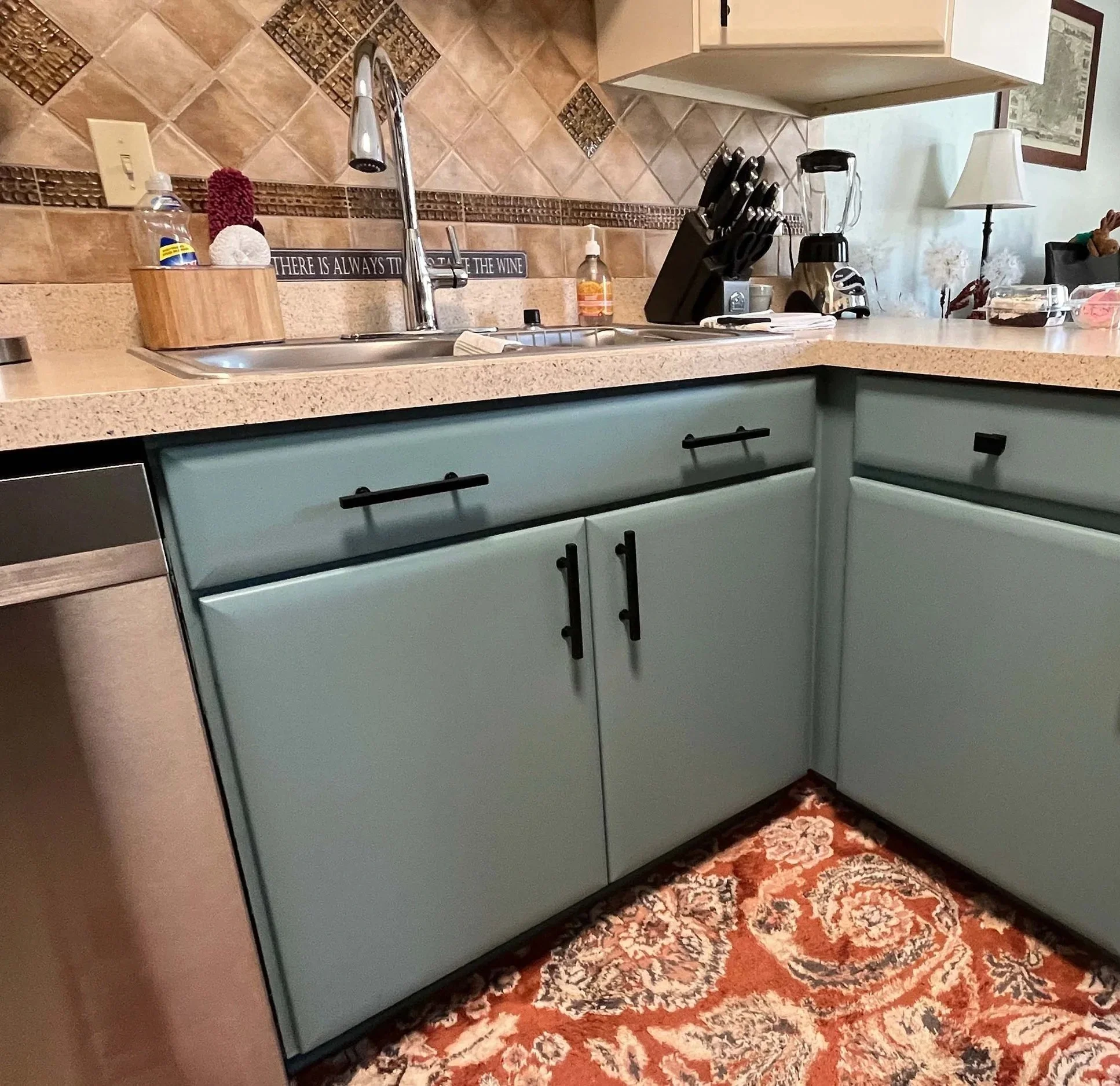Close up of kitchen cabinets professionally spray painted in a smooth teal finish by painting contractors in Minneapolis.