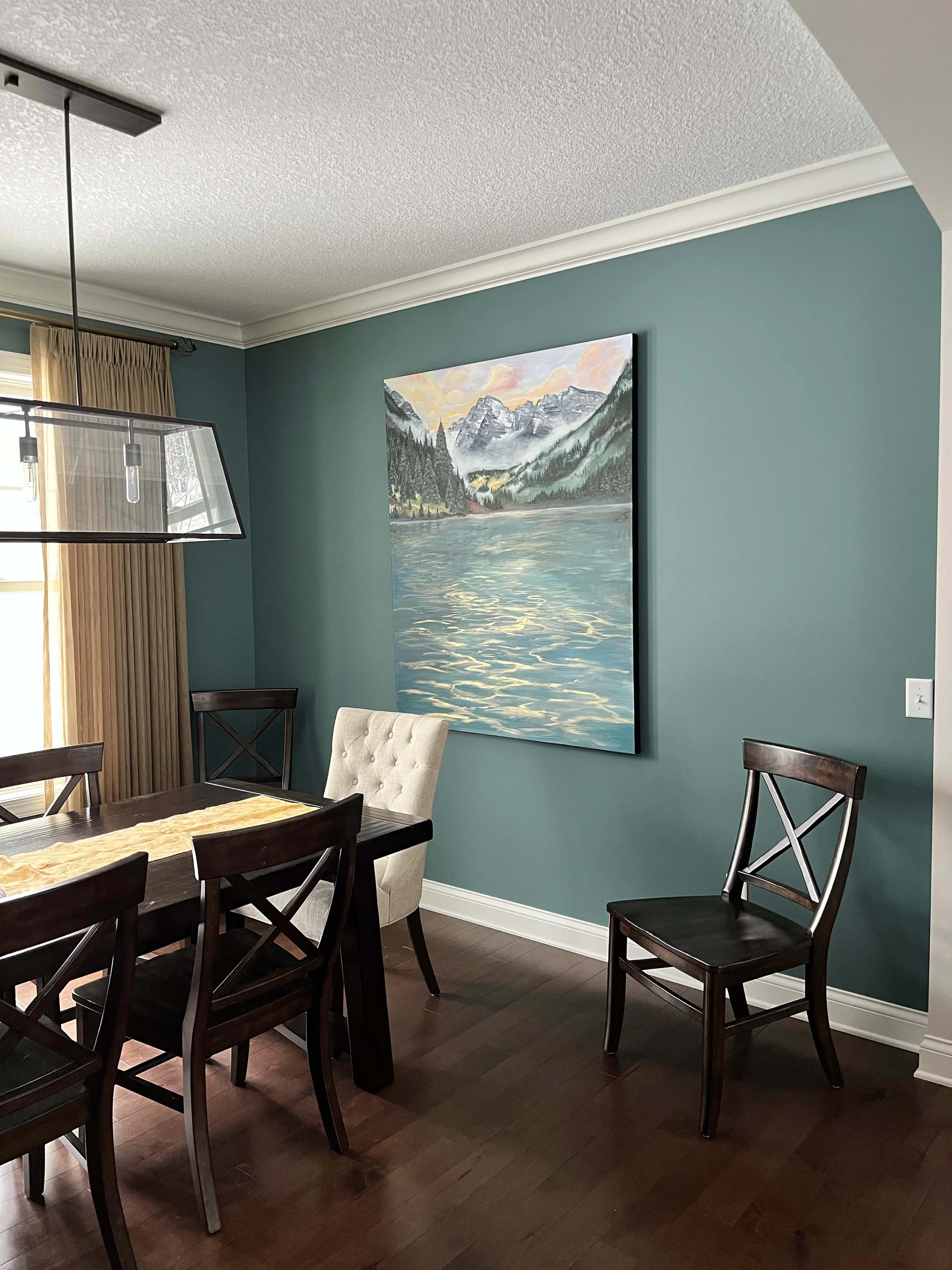 A sophisticated dining room featuring deep teal walls and white crown molding professionally finished by painting contractors in Minneapolis.