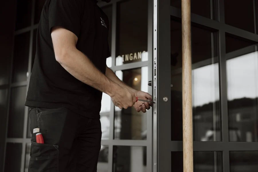 Ein Handwerker der SAG Sursee Schliesstechnik in Sursee montiert eine Glasschiebetür an einem modernen Gebäude.