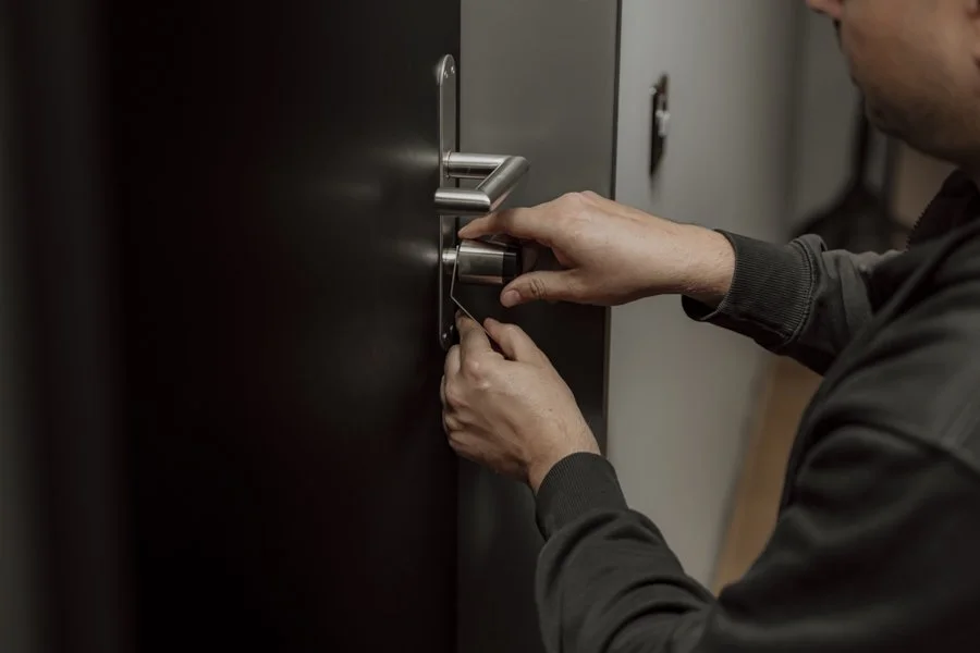 Eine Person sperrt einen schwarzen Tresor mit einem Schlüssel, der an einem Schloss unter dem Türgriff steckt.