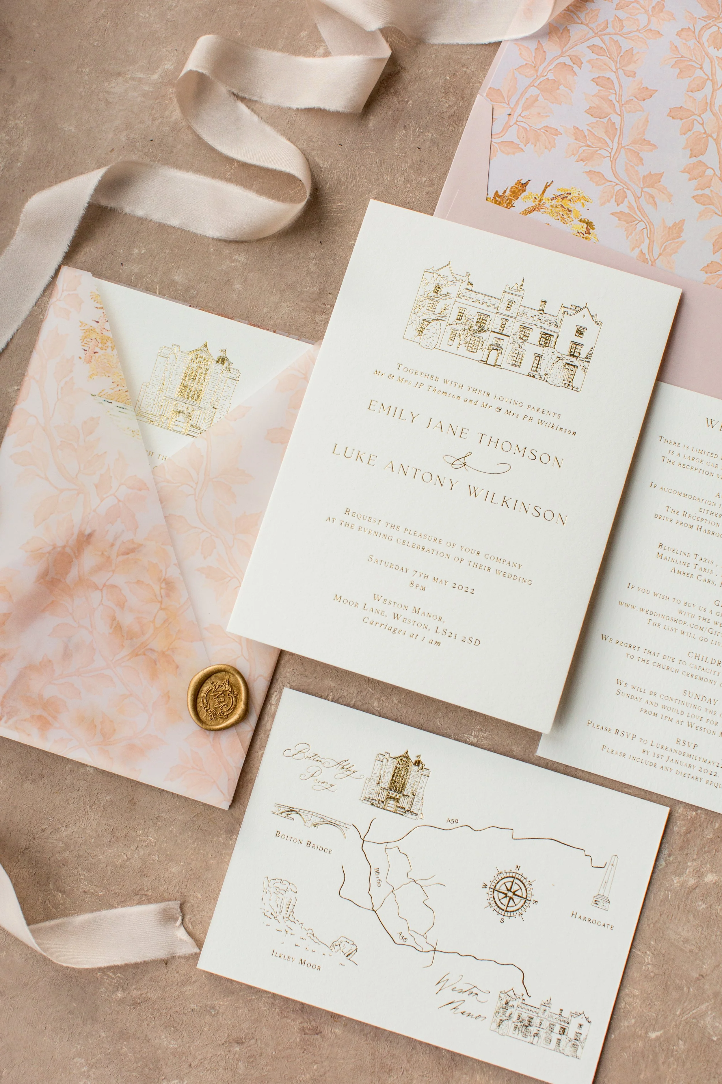 Wedding invitation suite with white and pink floral details, a map, and a gold wax seal.