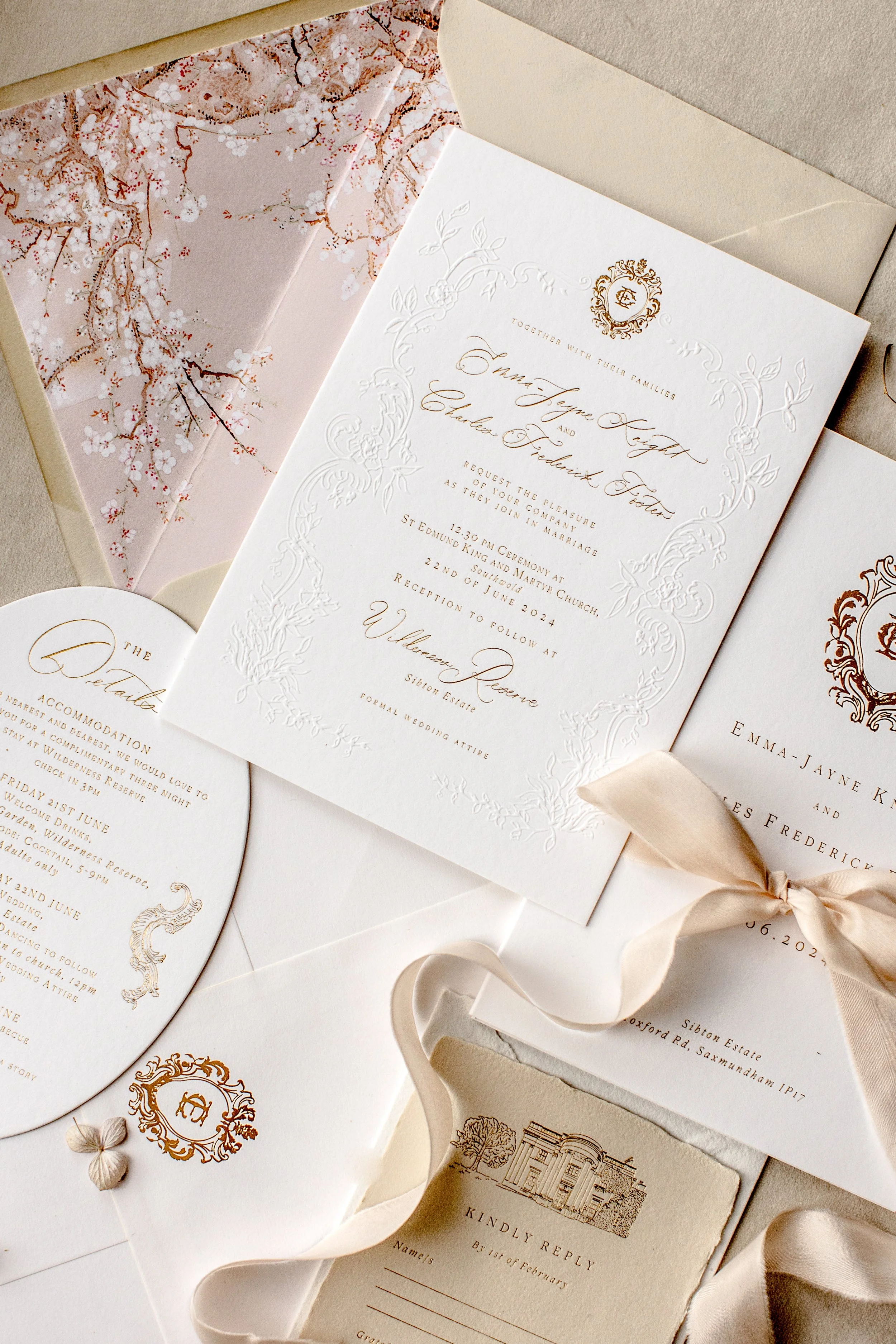 Elegant wedding invitation suite with floral details, monogram, and RSVP card, set against a neutral background with silk ribbon accents.