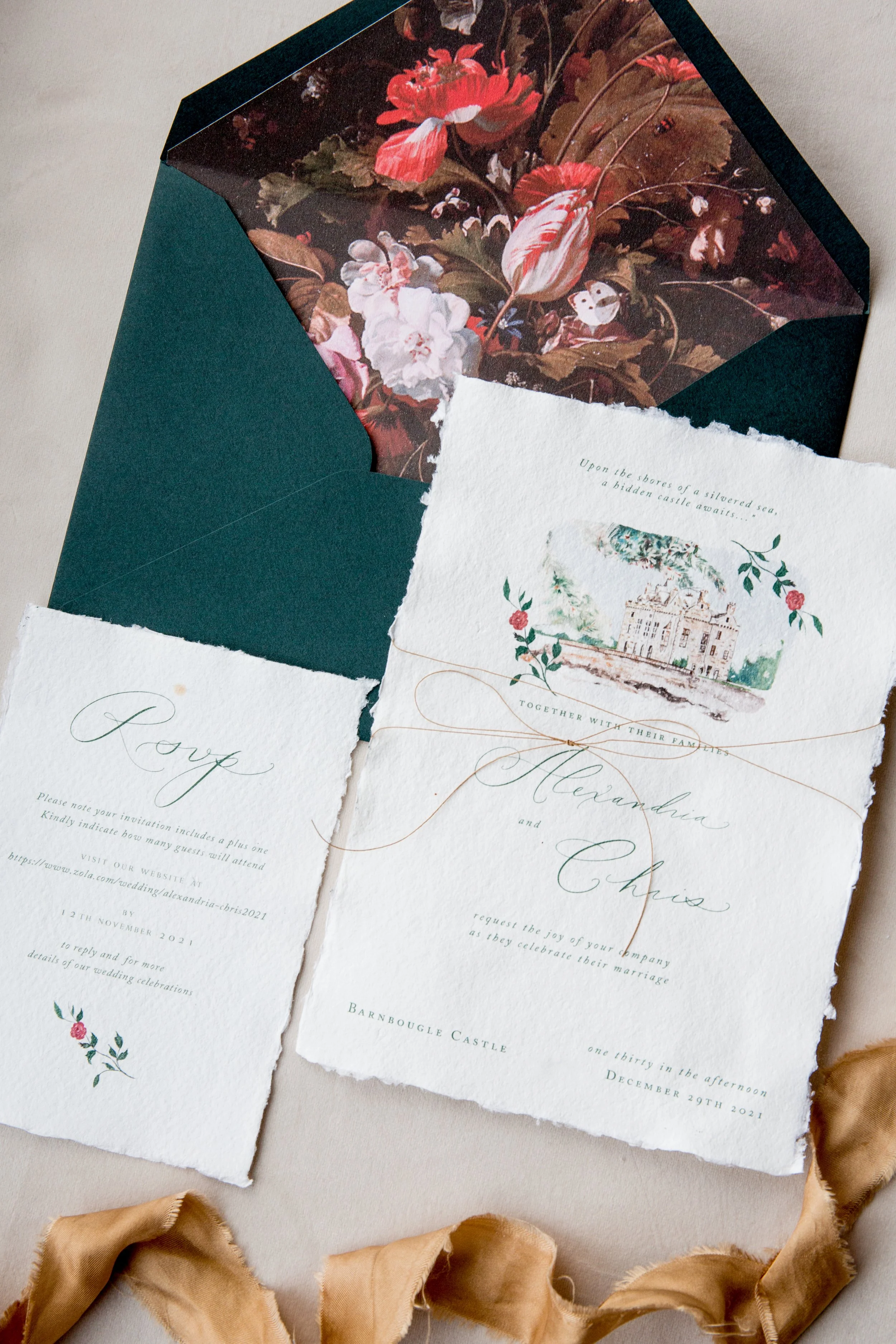 Castle Wedding invitation suite with floral details, placed on a light fabric background with a gold ribbon. Includes an envelope with a dark interior floral pattern.