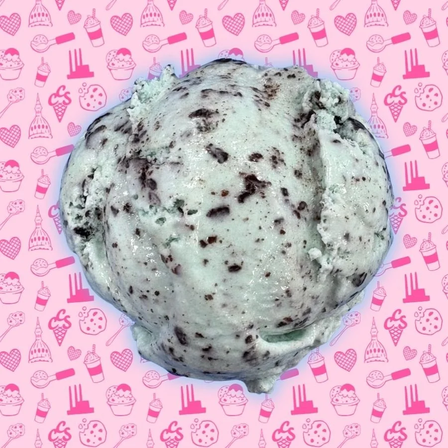 A scoop of mint chocolate chip ice cream on a pink background, featuring creamy pale green mint ice cream packed with rich chocolate flakes.