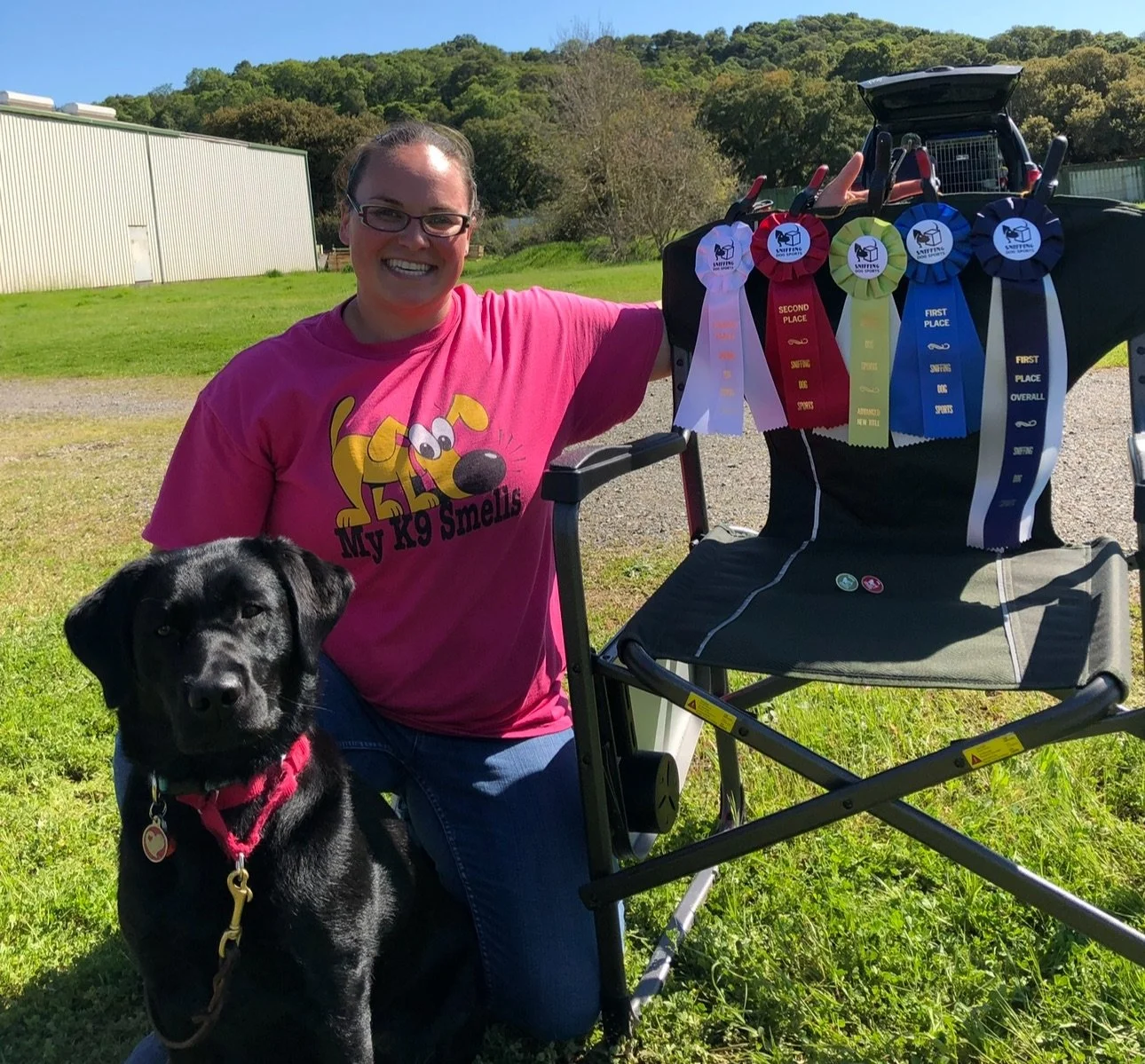 Dog training scent work instructor holding AKC Scent Work awards with her dog