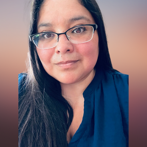 Close-up portrait of a woman with long dark hair and glasses, wearing a dark blue top, against a blurred gradient background.