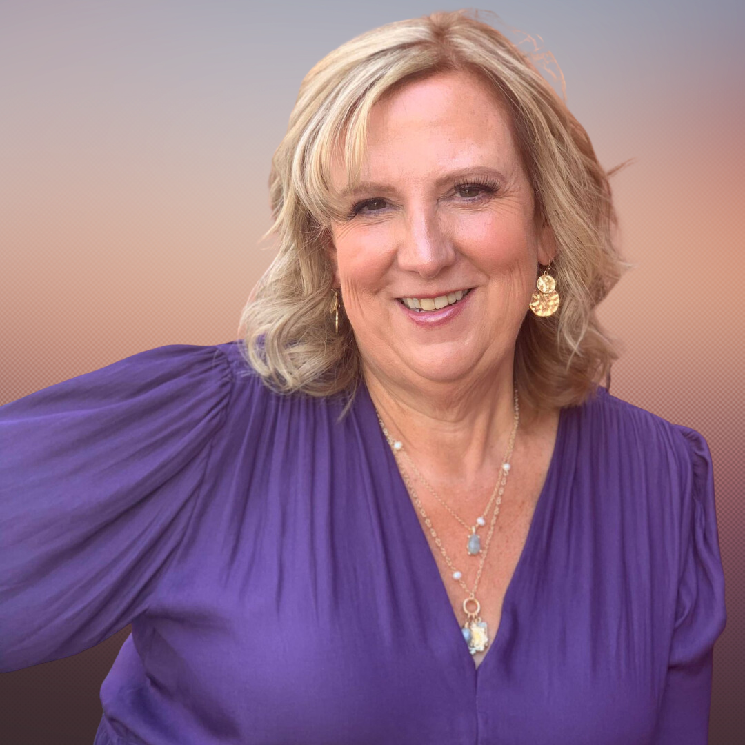 Portrait of a smiling blonde woman wearing a purple dress, gold earrings, and layered necklaces with a blue pendant, against a gradient background.