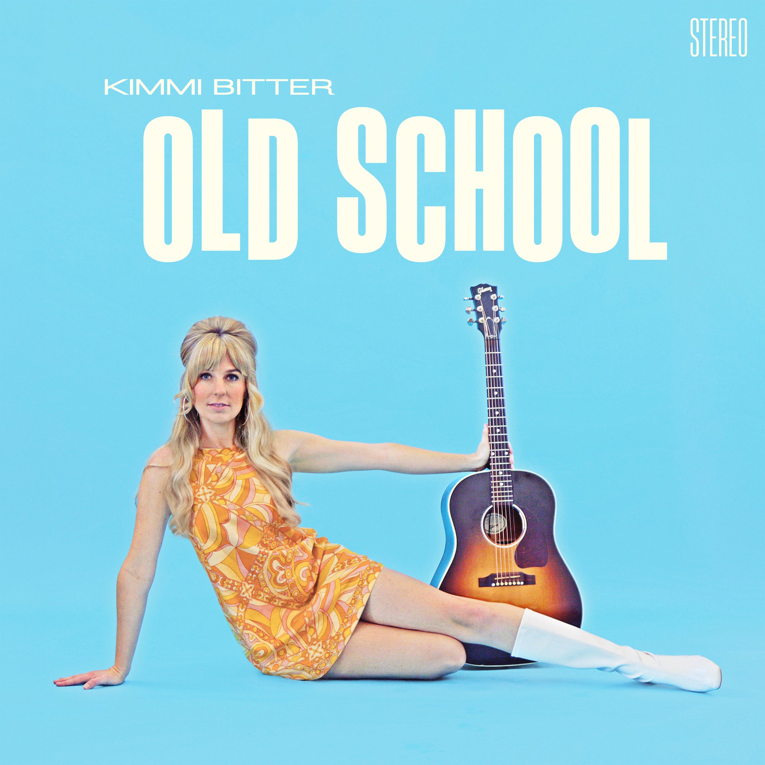 Album cover for Kimmi Bitter's 'Old School' featuring a woman with long blonde hair, wearing a colorful patterned dress, sitting on the floor with one arm extended to hold an acoustic guitar, against a solid light blue background.