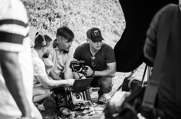 Group of people working on a film or video production outdoors, with cameras and equipment.