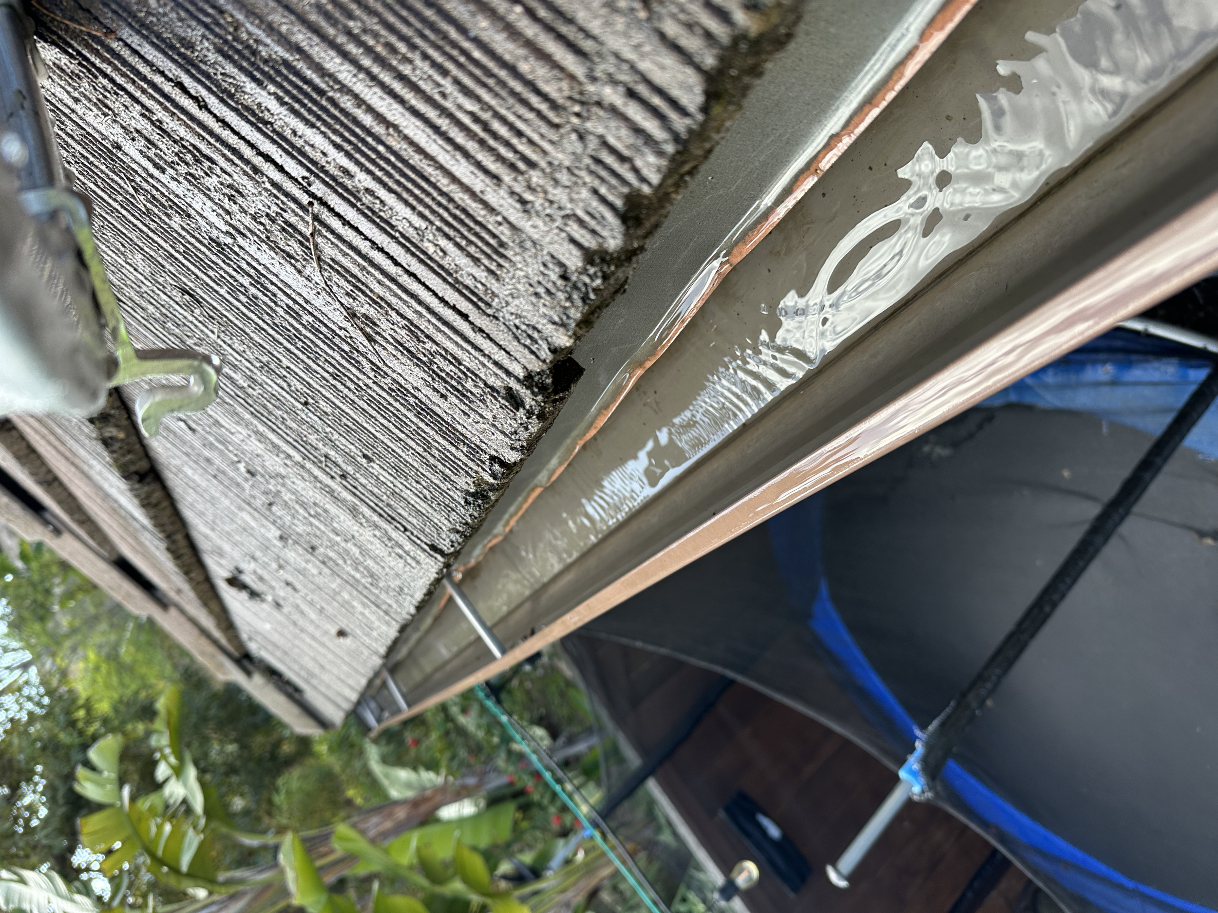 Close-up of a house exterior with a wooden siding and window trim, showing fresh sealant or caulking around the window frame.