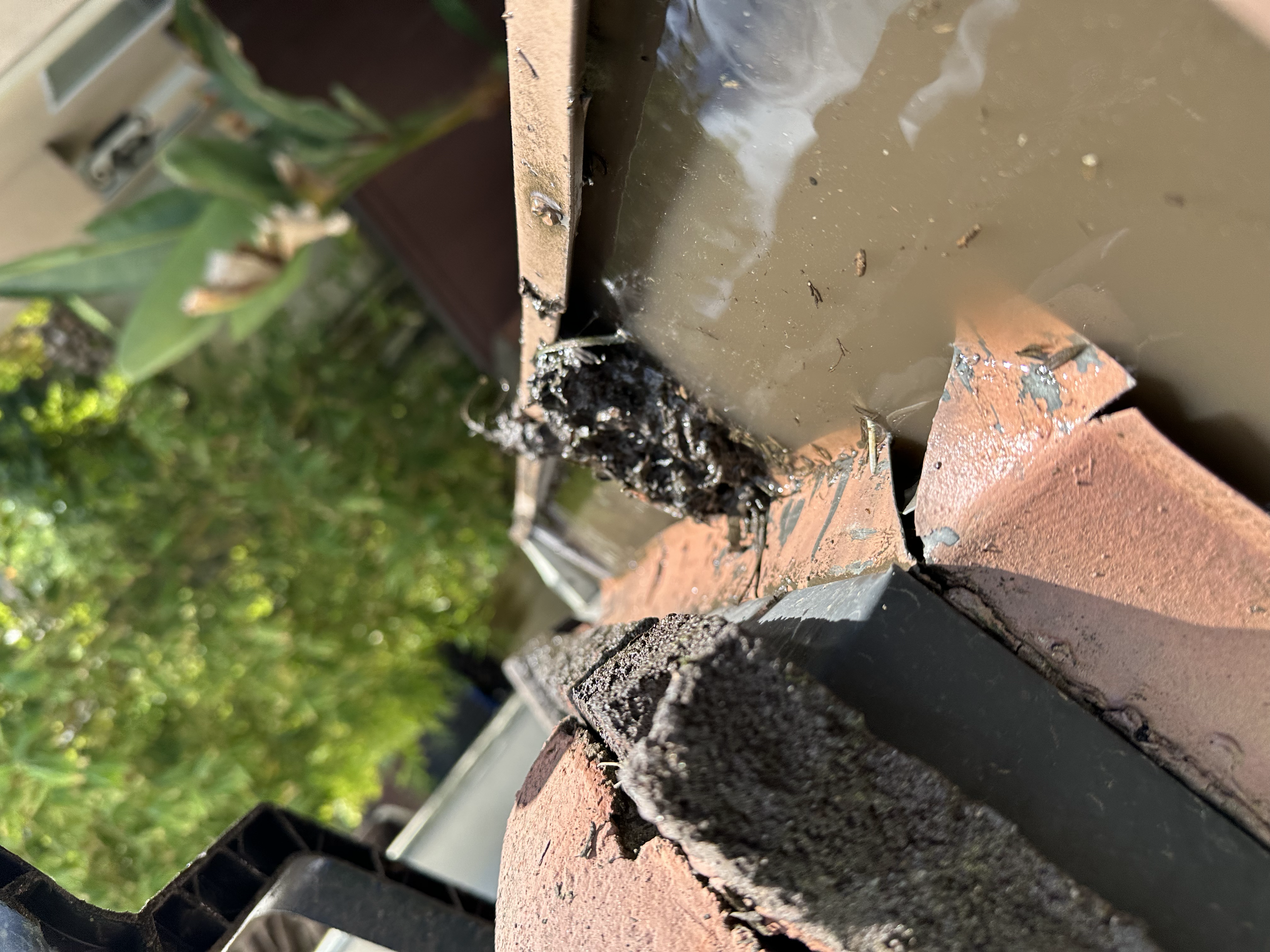 Close-up of a brick wall corner with damaged brick, some black debris and water damage.