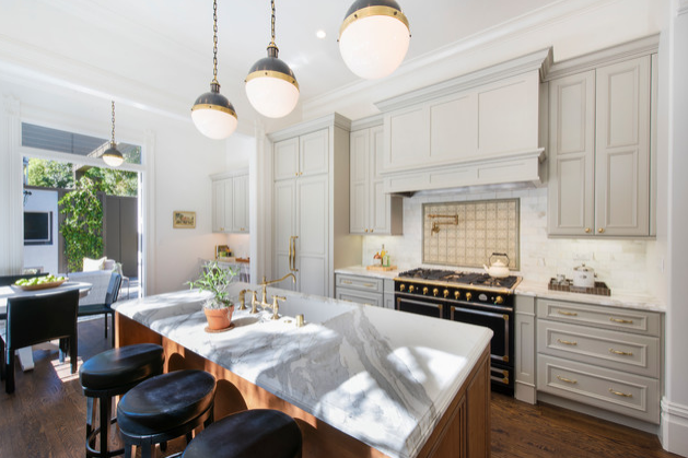 Modern kitchen with white cabinetry, marble island, black stove, and hanging pendant lights.