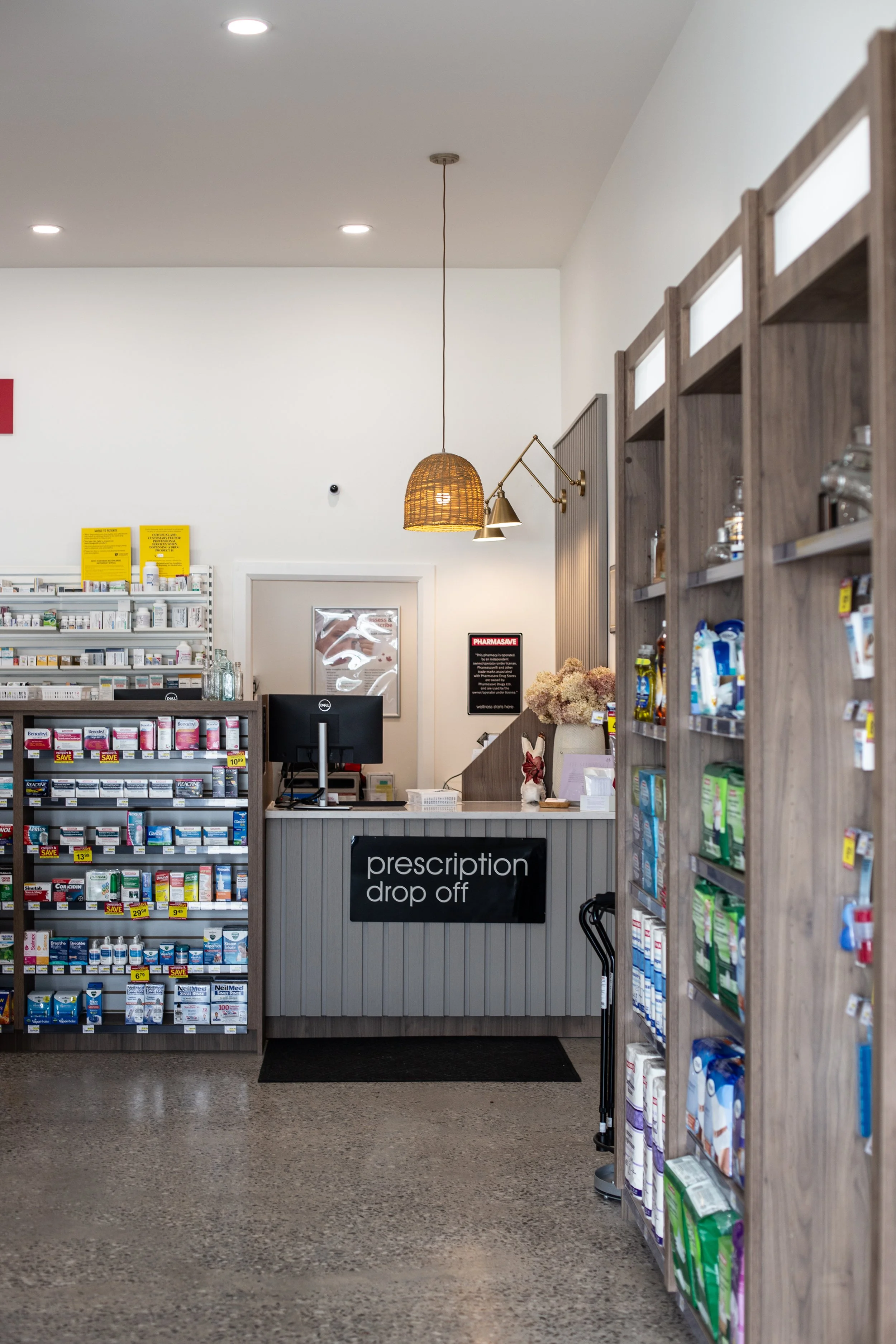 Inside a pharmacy store, a checkout counter labeled 'prescription drop off' is visible with shelves of medication and healthcare products surrounding it.