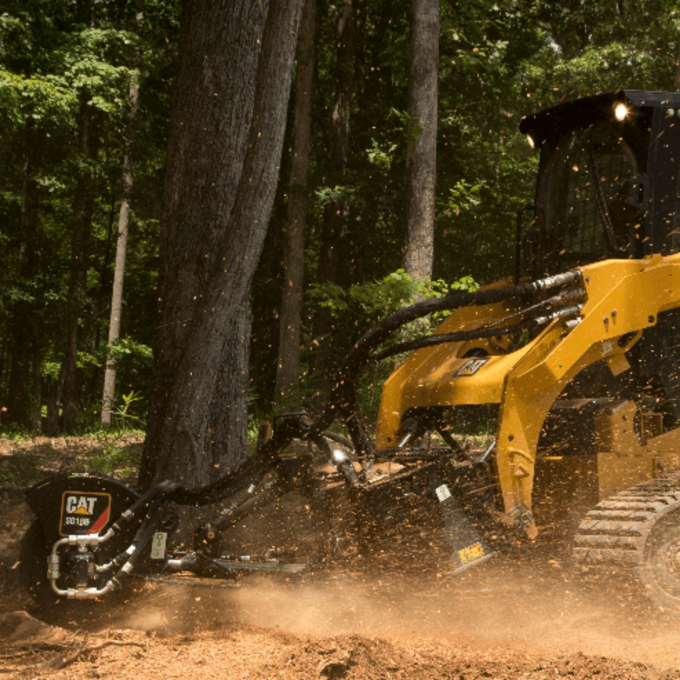 A yellow bulldozer with black tracks clearing a wooded area with dirt flying up.