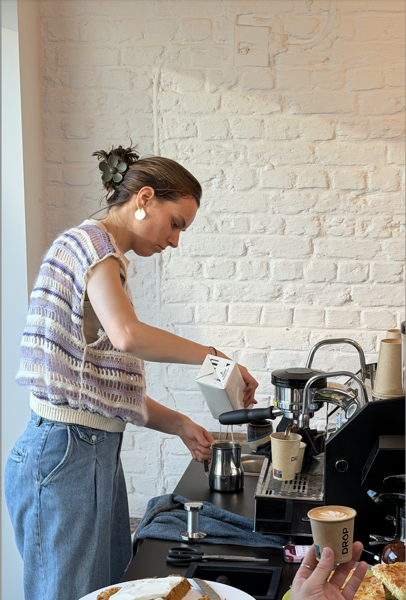 A barista making coffee behind the mobile coffee cart Drop. She is pouring plant-based milk into a pitcher.
