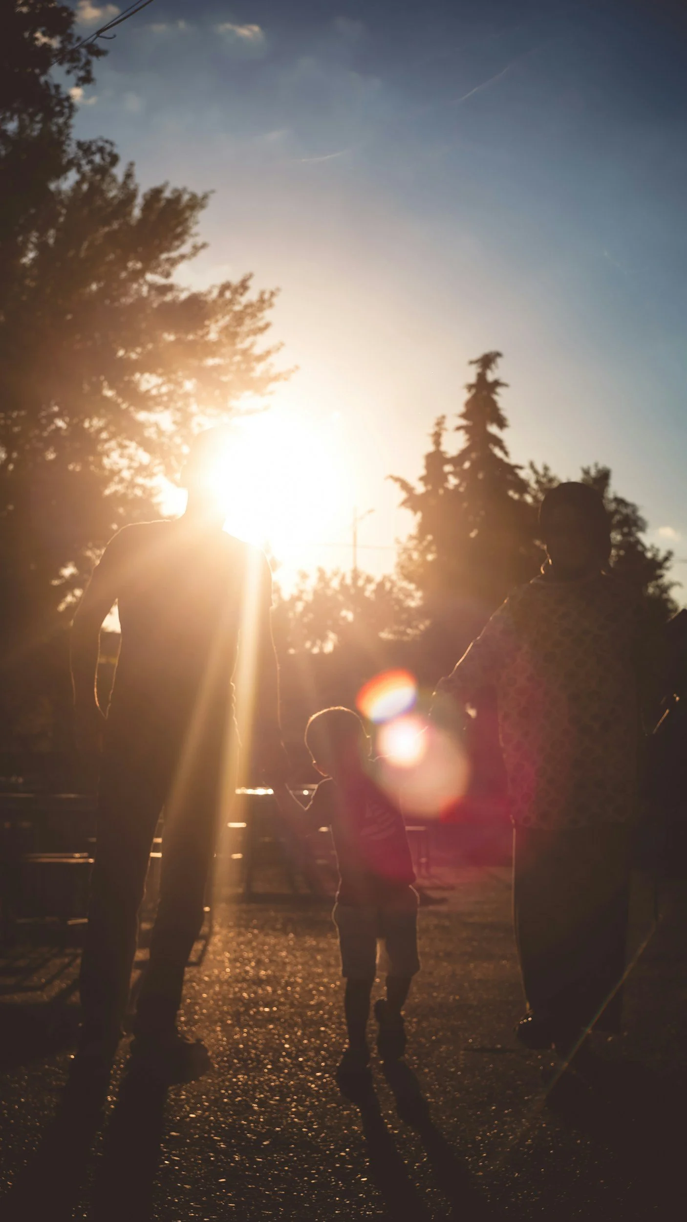 Parents and child standing together outdoors in sunlight, representing warmth and connection
