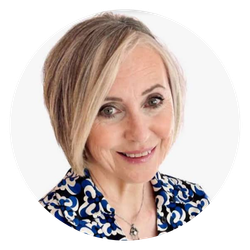 Smiling woman with short blonde hair wearing a blue and white patterned blouse