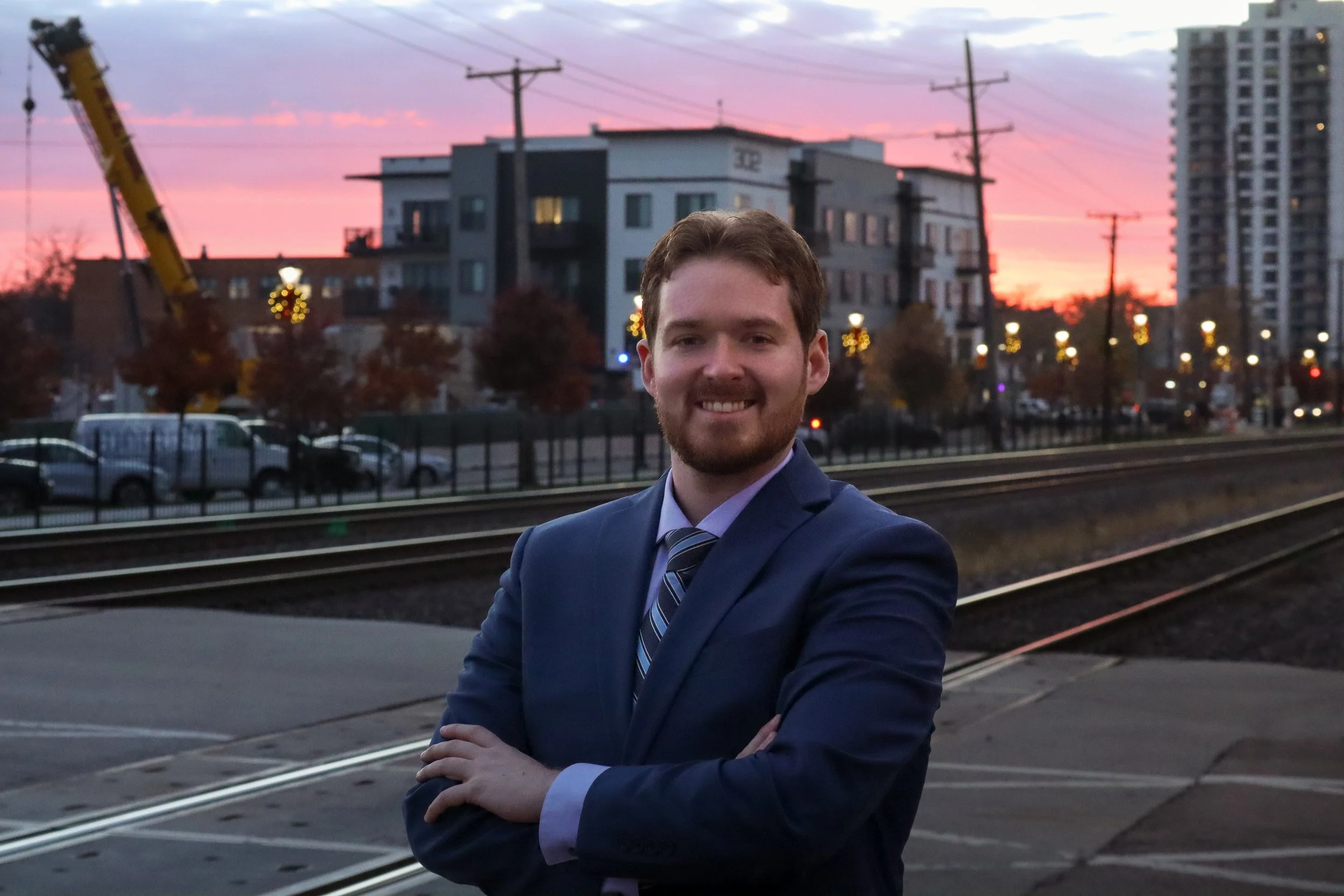 Ben McAdams smiles in front of Metra tracks in a blue suit.