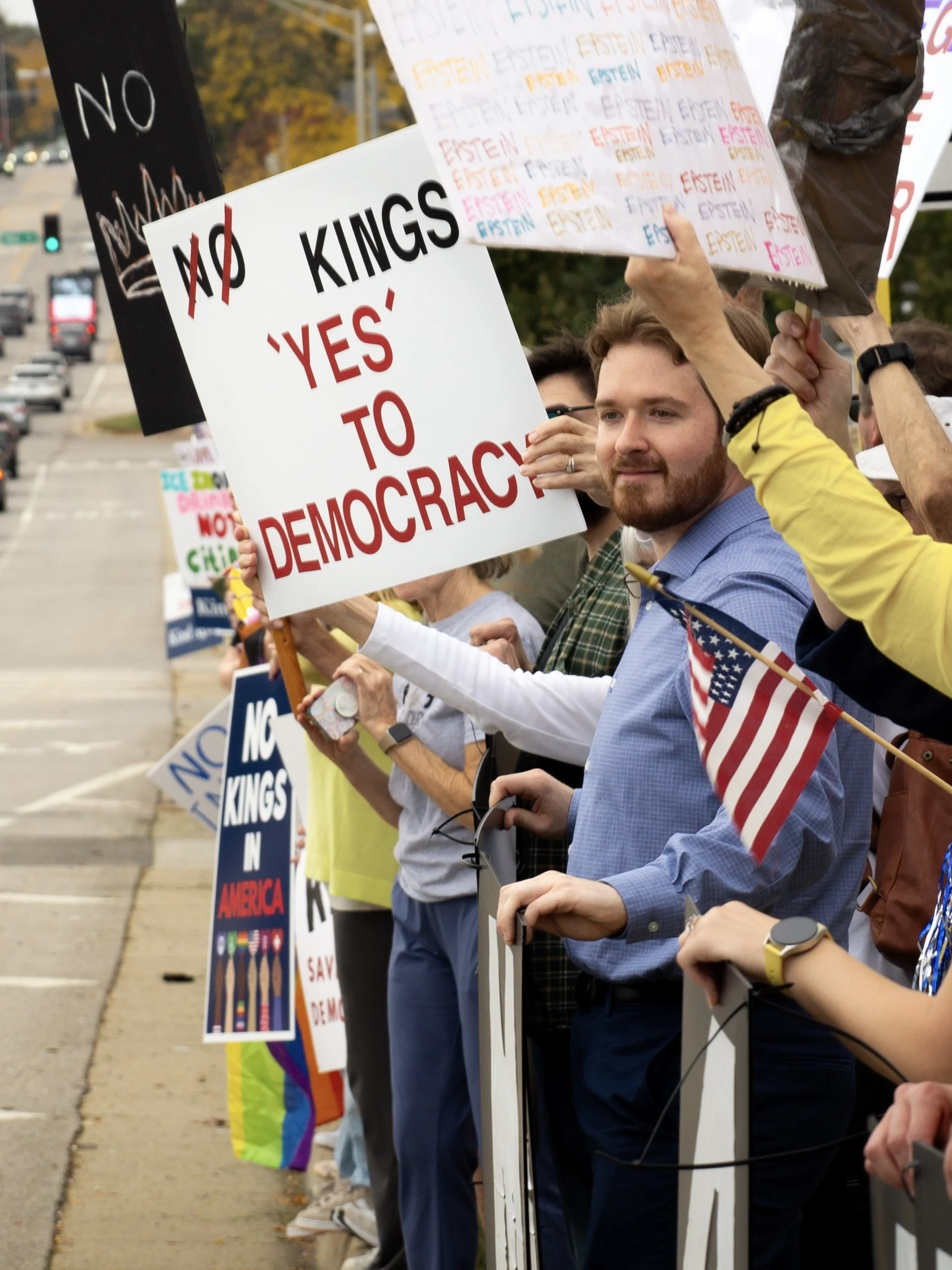 Ben McAdams looks on in a crowd at the No Kings Protest. He holds a sign that says No Kings. 'Yes' to Democracy.