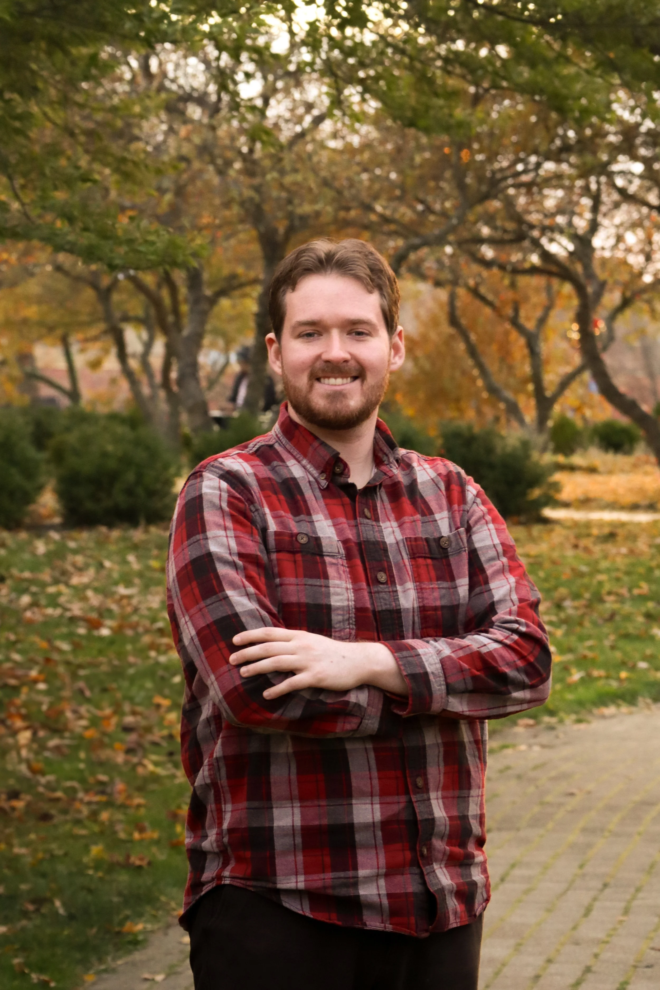 Ben McAdams stands with crossed arms in a red flannel and is smiling