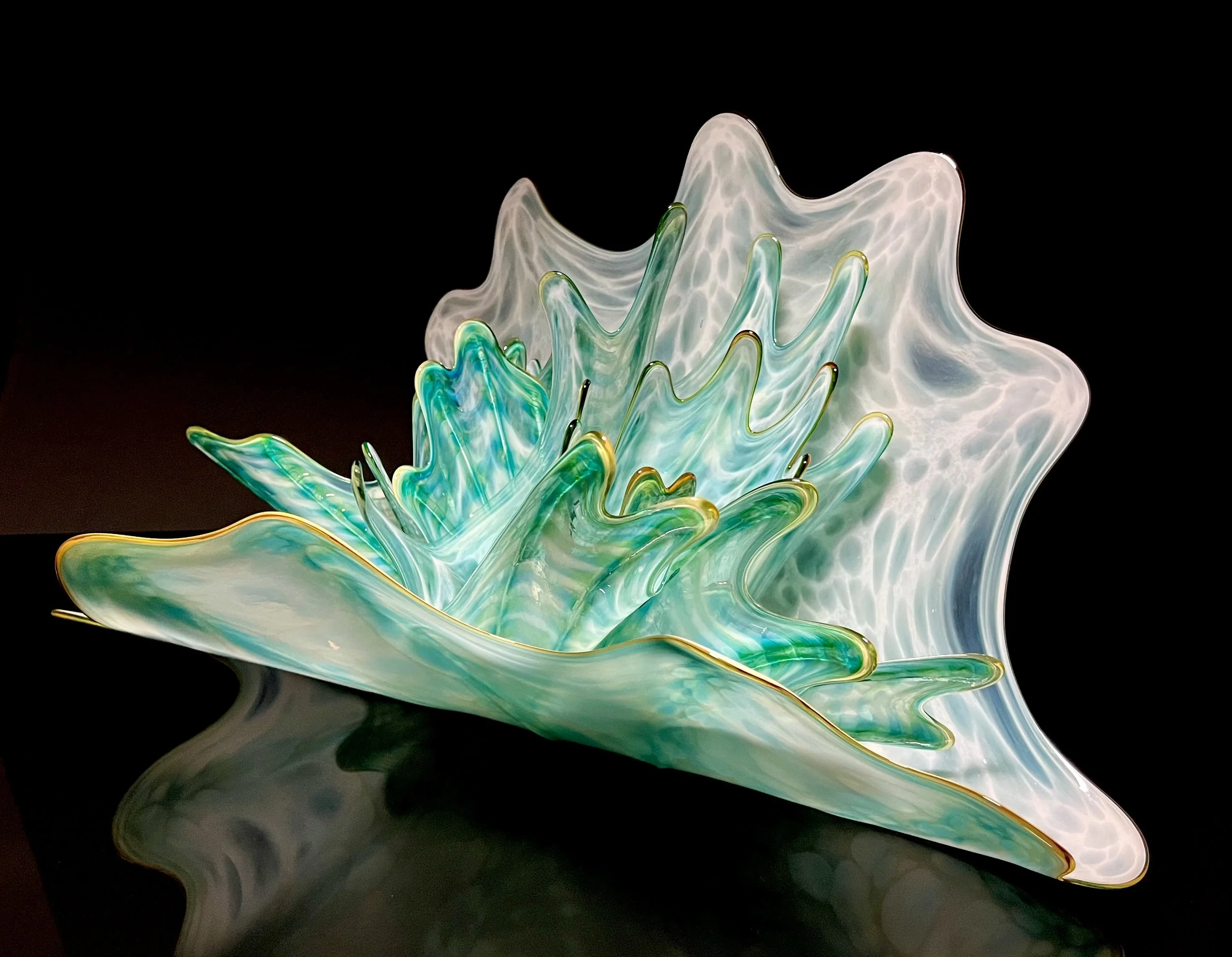 Colorful glass sculpture resembling an abstract flower on a black background.