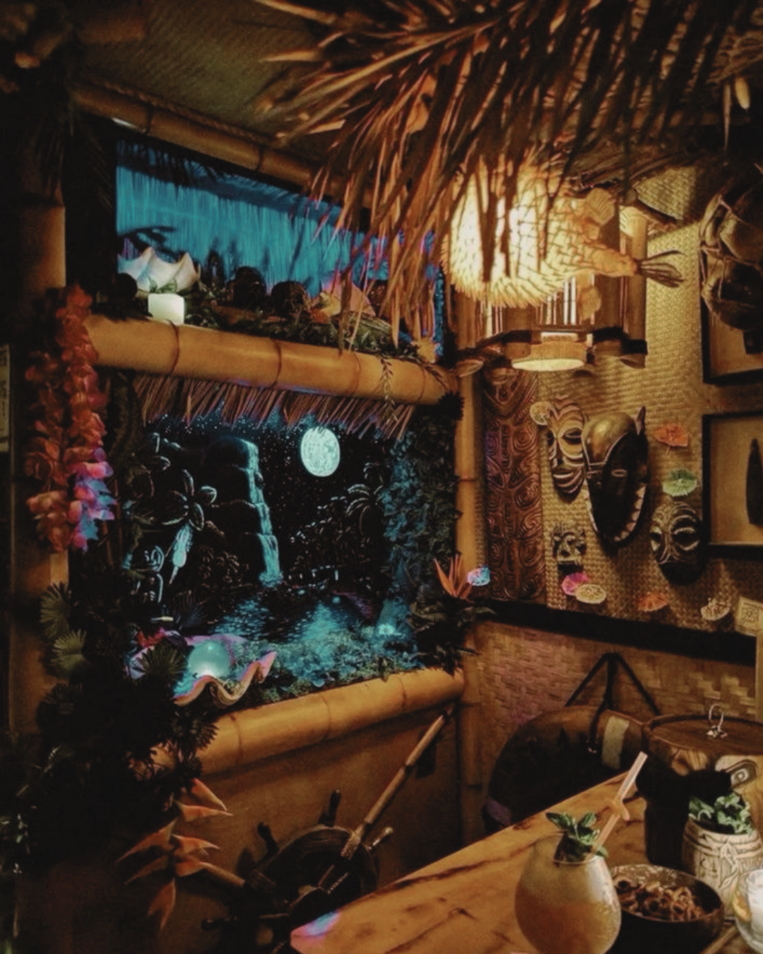 Tropical-themed room with bamboo decor, tribal masks, and a large mural of a moonlit waterfall scene.